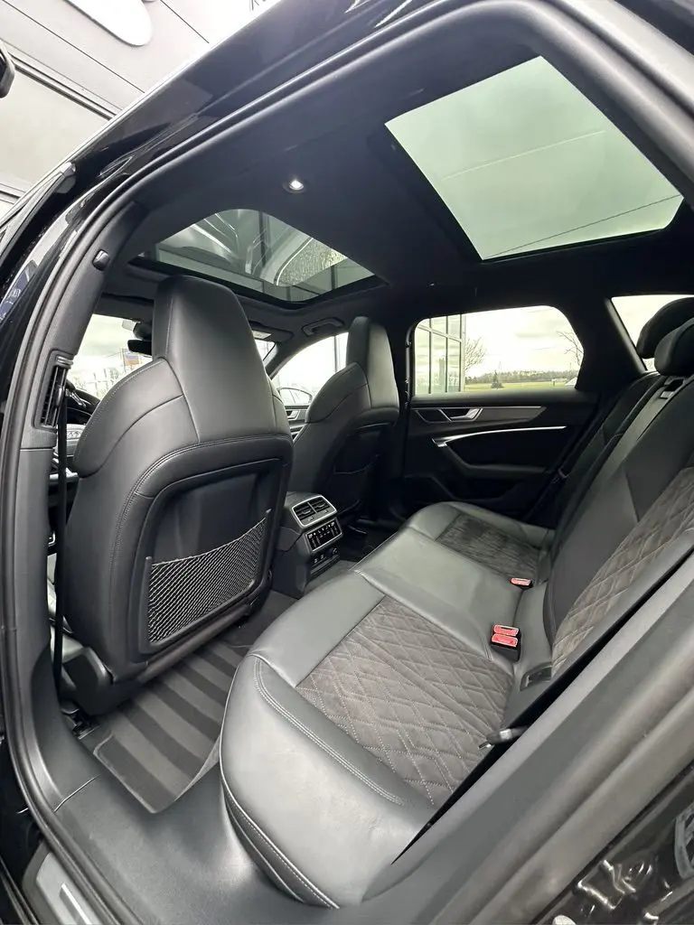 Vue intérieure arrière de l'Audi RS6 Avant noire 2021, montrant les sièges en cuir et le toit ouvrant panoramique.