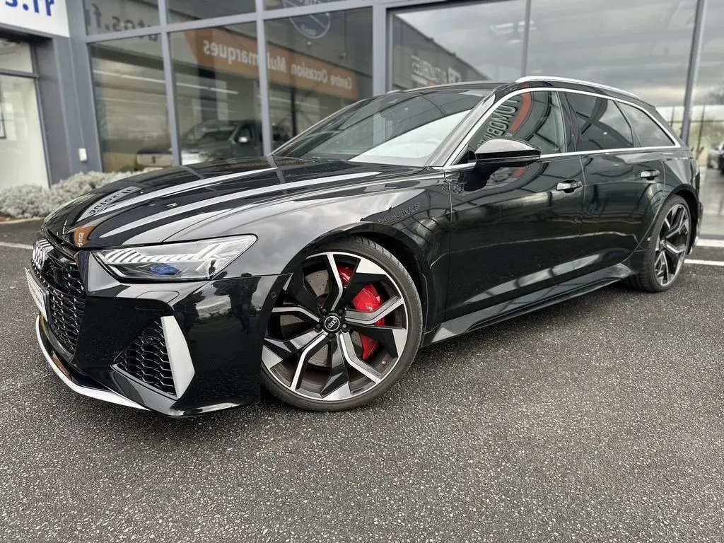Audi RS6 Avant noire vue en 3/4 avant droit, avec jantes sport et étriers de frein rouges visibles.