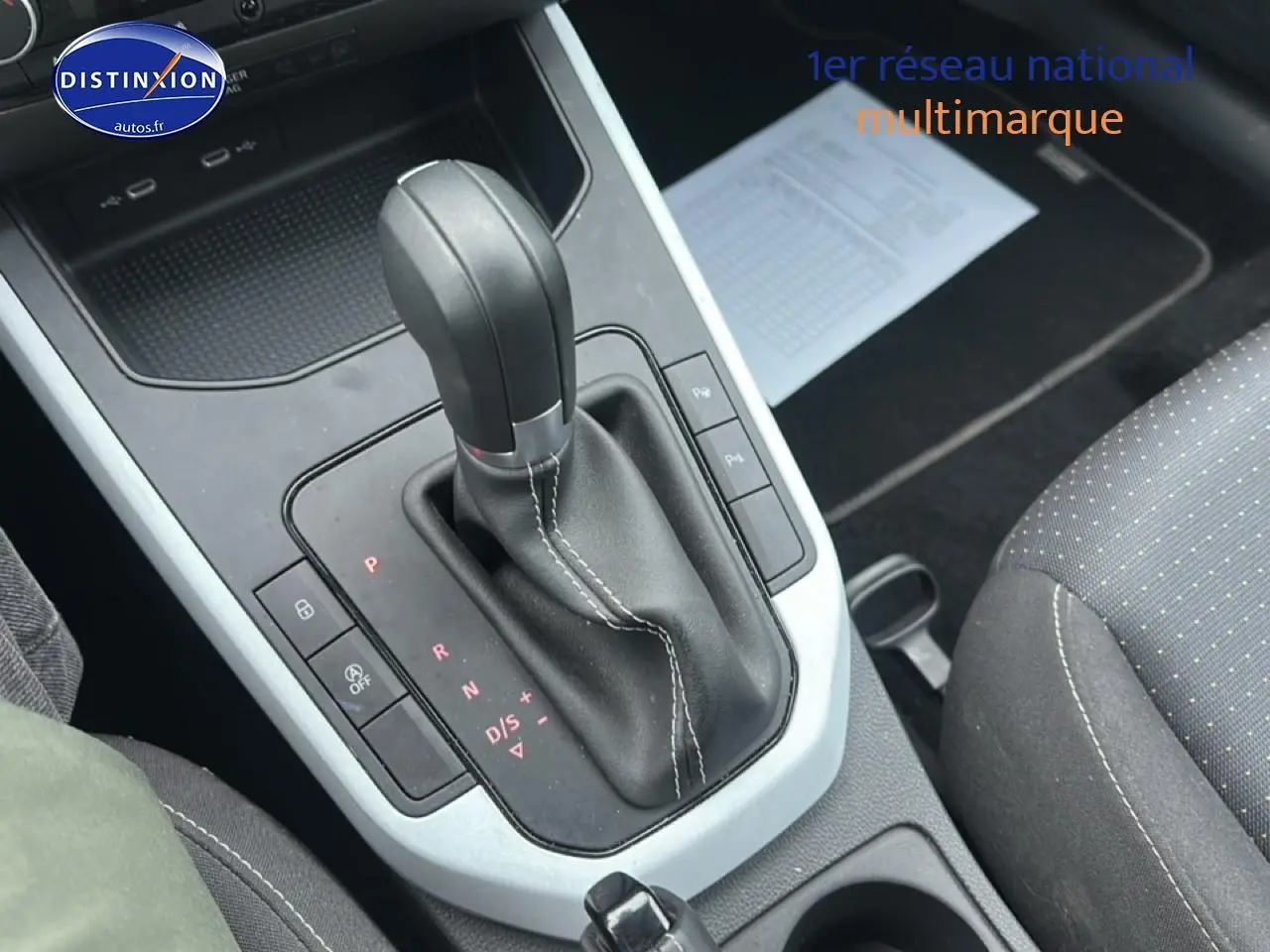 Levier de boîte automatique noir avec surpiqûres blanches dans l’habitacle d’une SEAT Arona bleu saphir 2025.