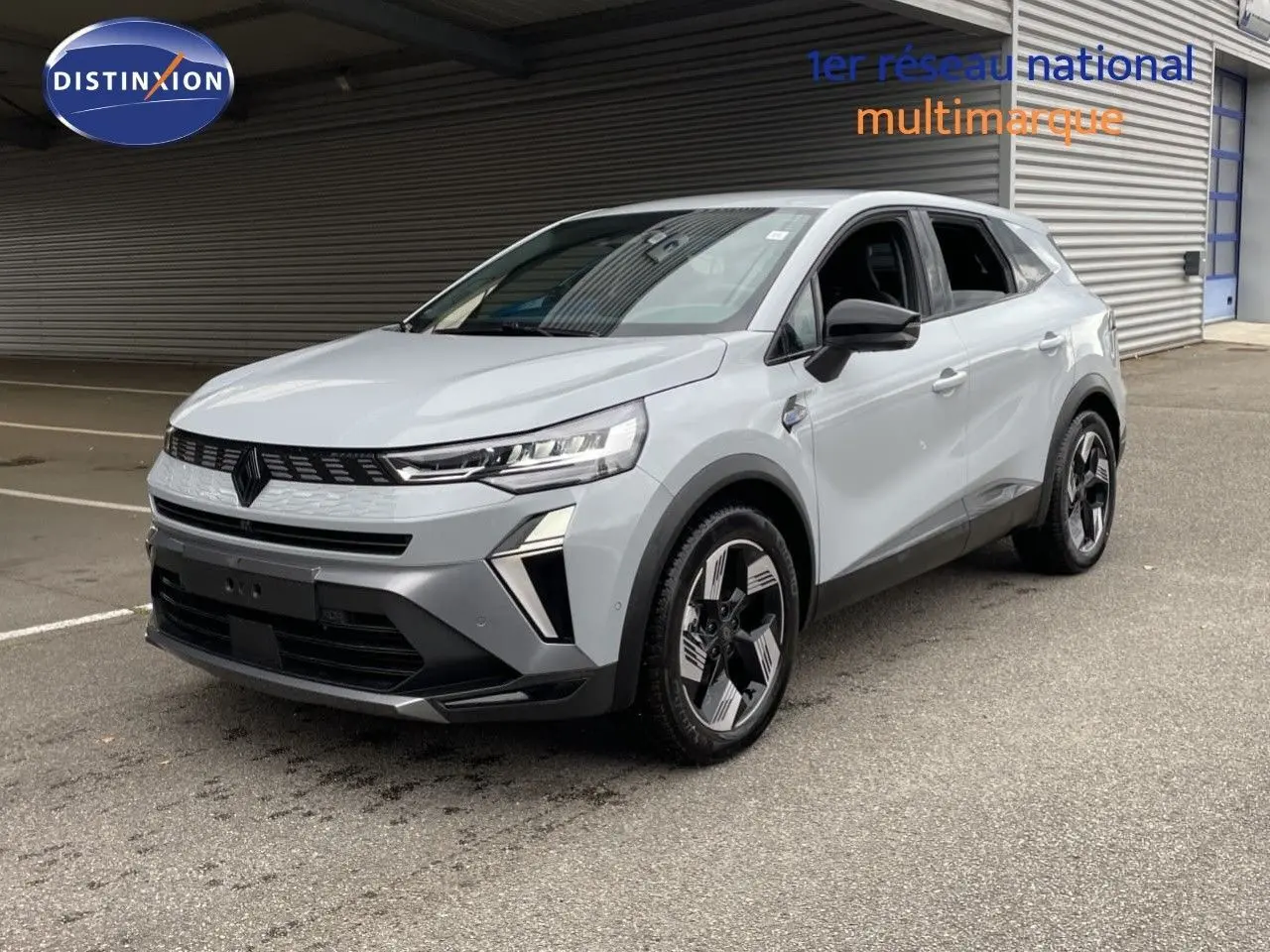 Renault Symbioz gris Rafale métal en 3/4 avant droit, SUV hybride avec jantes bicolores et calandre noire distinctive.