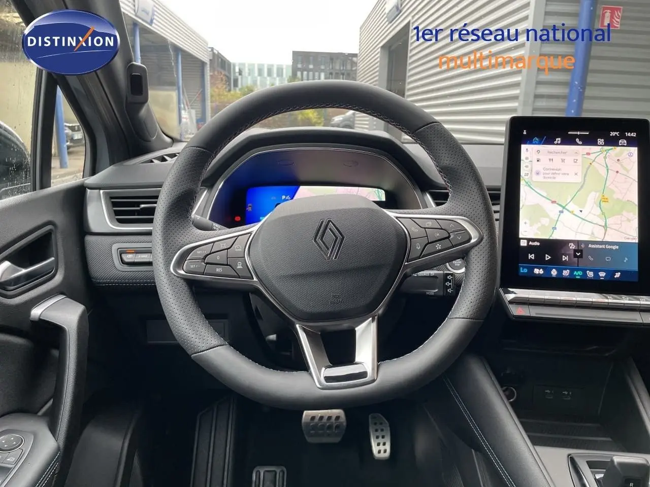 Vue frontale de l'intérieur du Renault Symbioz gris Rafale, volant multifonction et écran tactile avec navigation affichée.