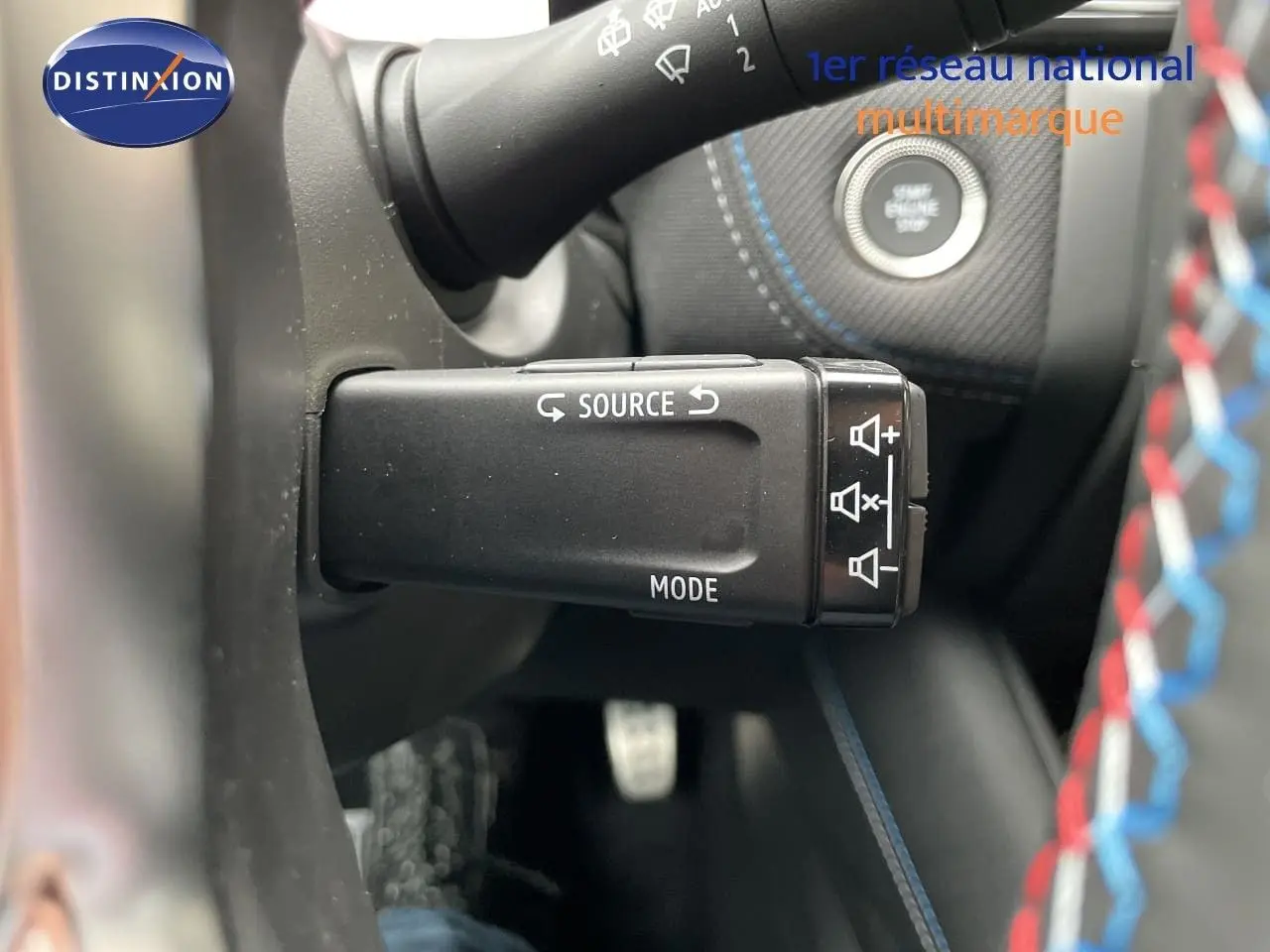 Gros plan sur la commande multimédia au volant du Renault Symbioz gris Rafale, avec démarreur et coutures bleues visibles.