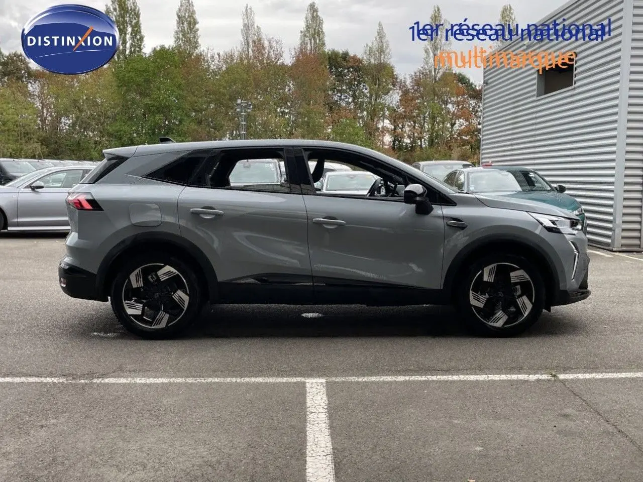 Vue latérale droite d'un Renault Symbioz gris rafale métal, SUV hybride avec jantes noires et détails modernes.