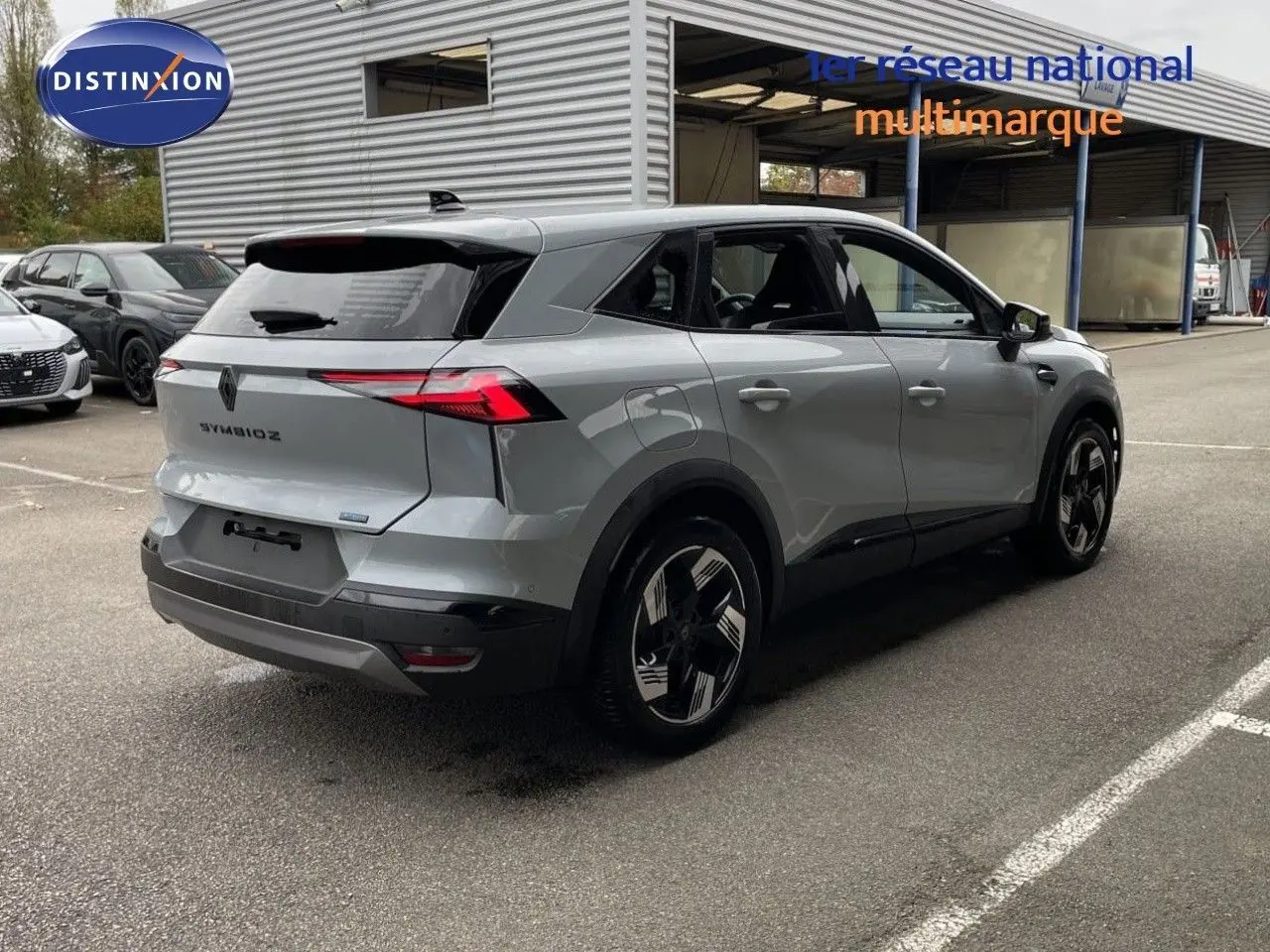 Renault Symbioz gris Rafale métal en 3/4 arrière droit, mettant en valeur ses feux LED fins et ses jantes bicolores.