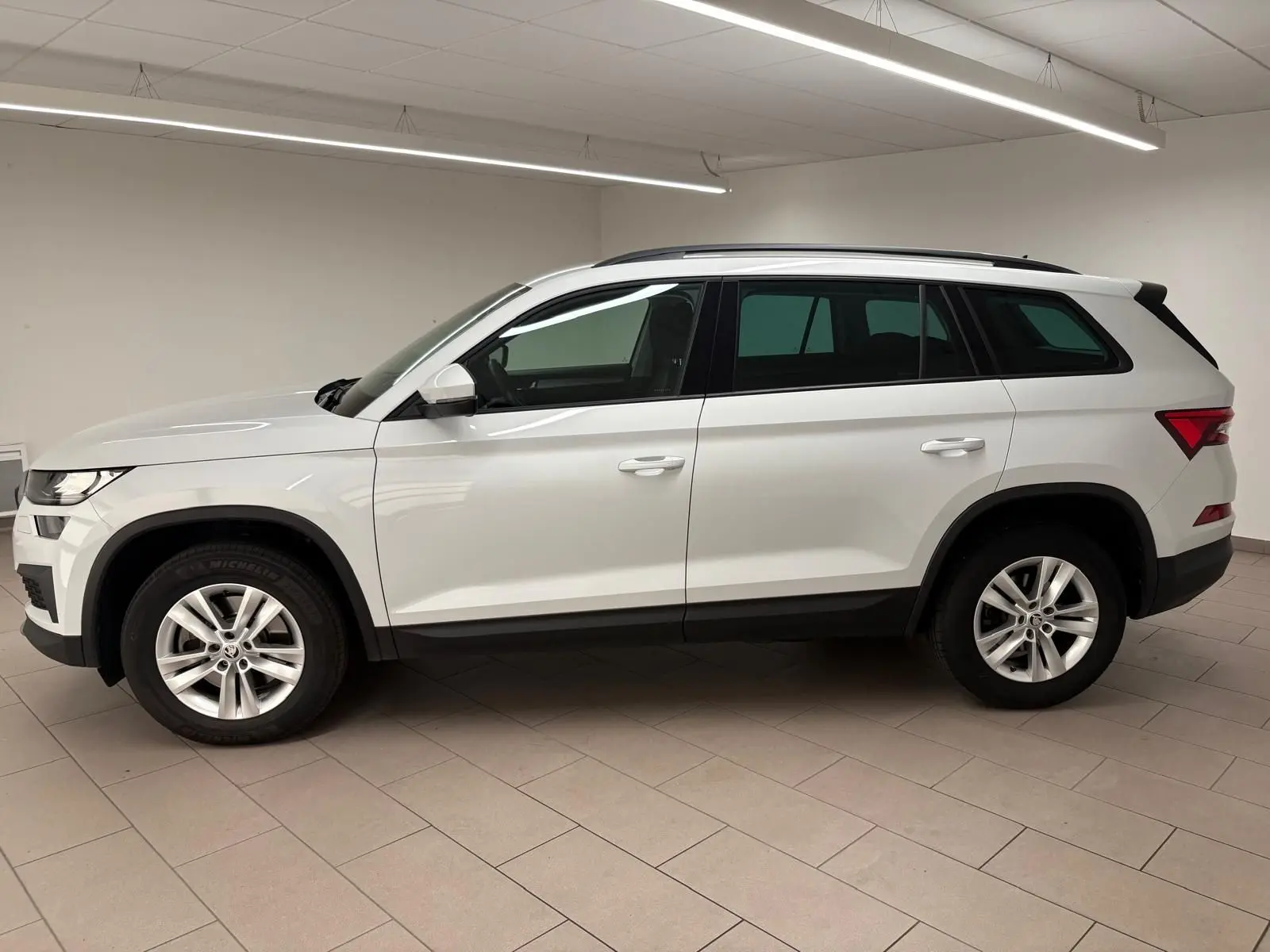 Profil côté gauche du SUV blanc SKODA KODIAQ 2022 avec jantes alliage et attelage escamotable visible à l'arrière.