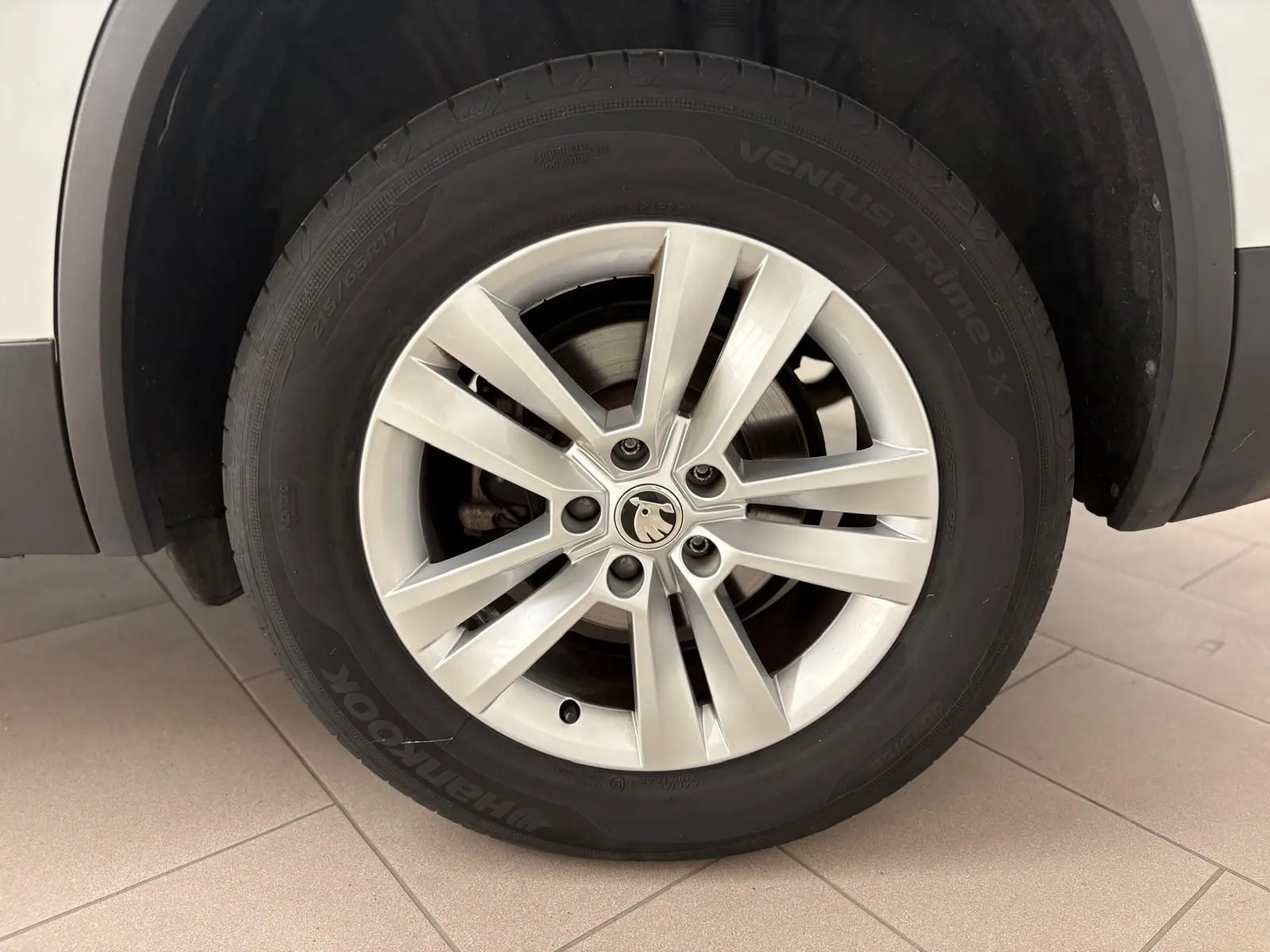 Gros plan sur la roue avant droite blanche lune d'un Skoda Kodiaq 2022 avec jante alliage et logo central visible.