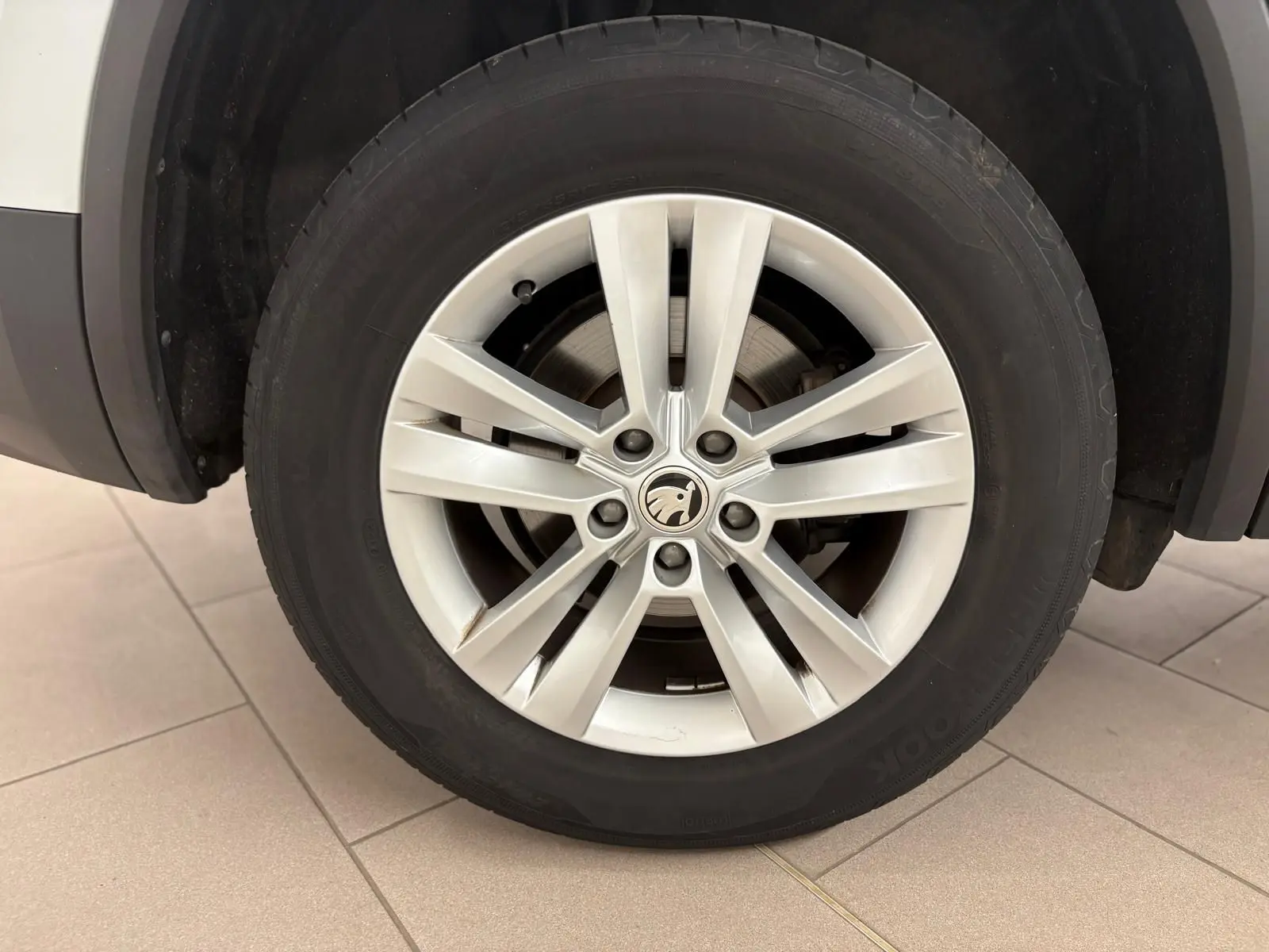 Gros plan sur la roue avant gauche du Skoda Kodiaq blanc Lune, mettant en valeur la jante alliage à 10 branches.