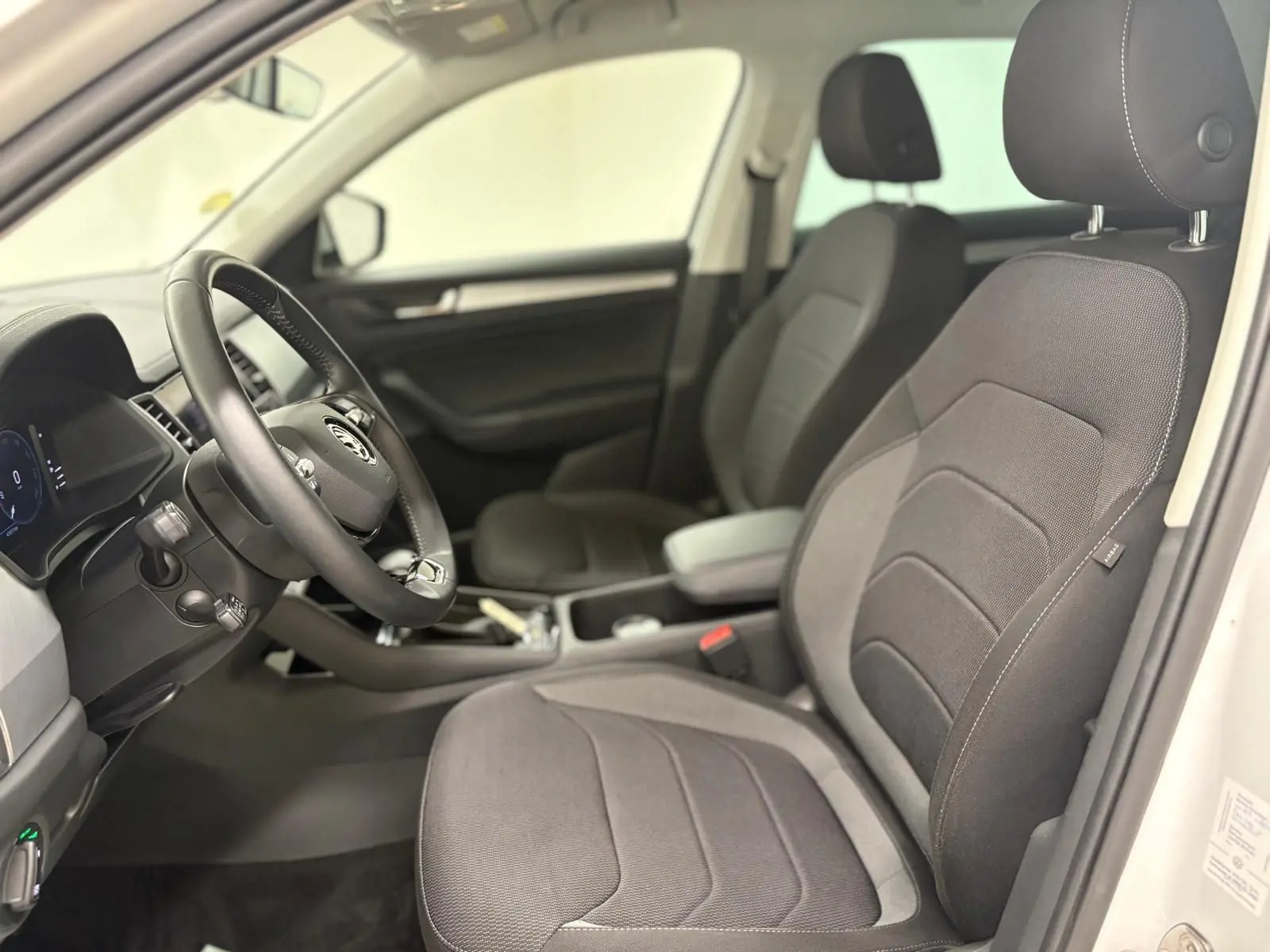 Intérieur vu côté conducteur du Skoda Kodiaq blanc lune 2022, sièges tissu gris et tableau de bord avec Digital Cockpit.