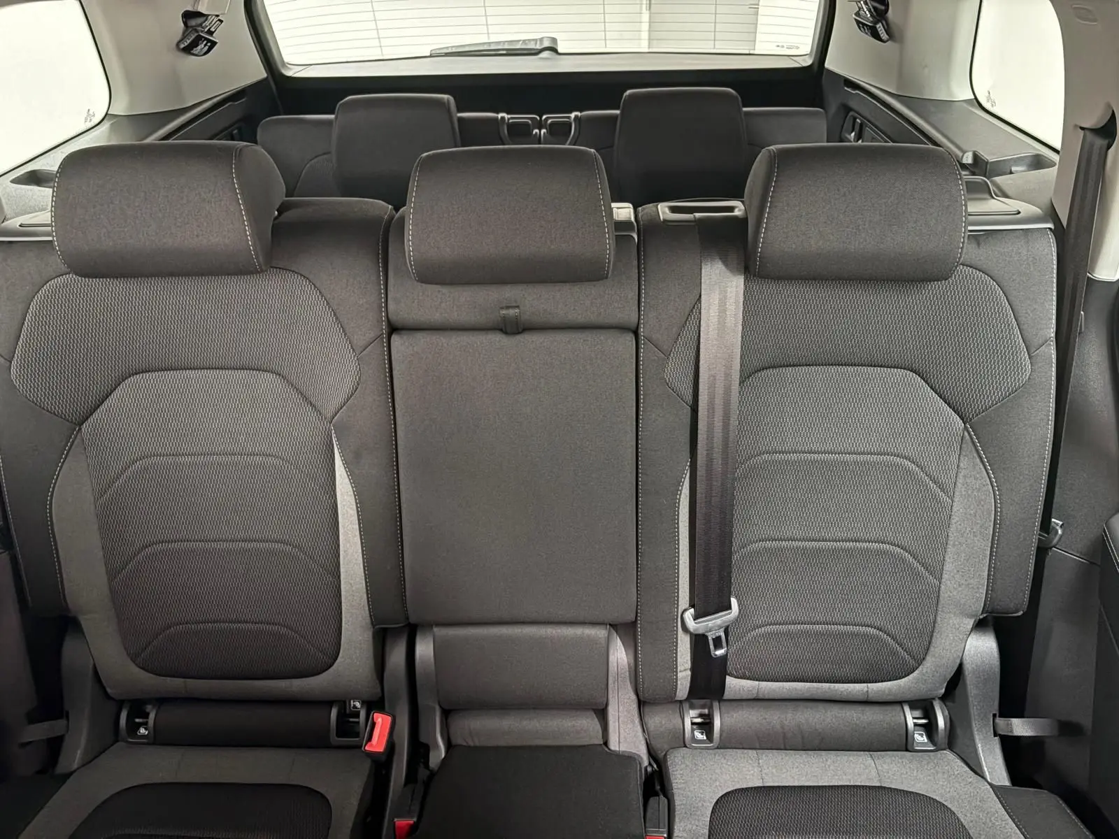 Vue arrière des sièges noirs du rang 2 du Skoda Kodiaq blanc lune 2022 avec banquette rabattable et ceinture visible.