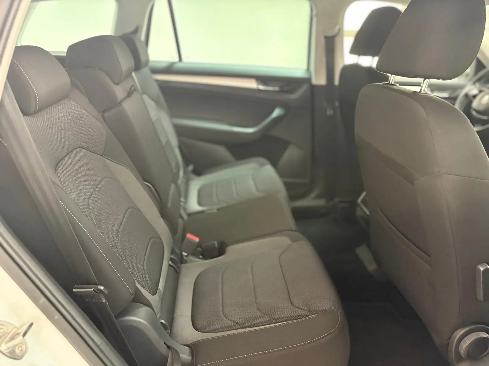 Vue intérieure côté gauche sur la banquette arrière noire du Skoda Kodiaq blanc Lune 2022 avec finitions sobres.