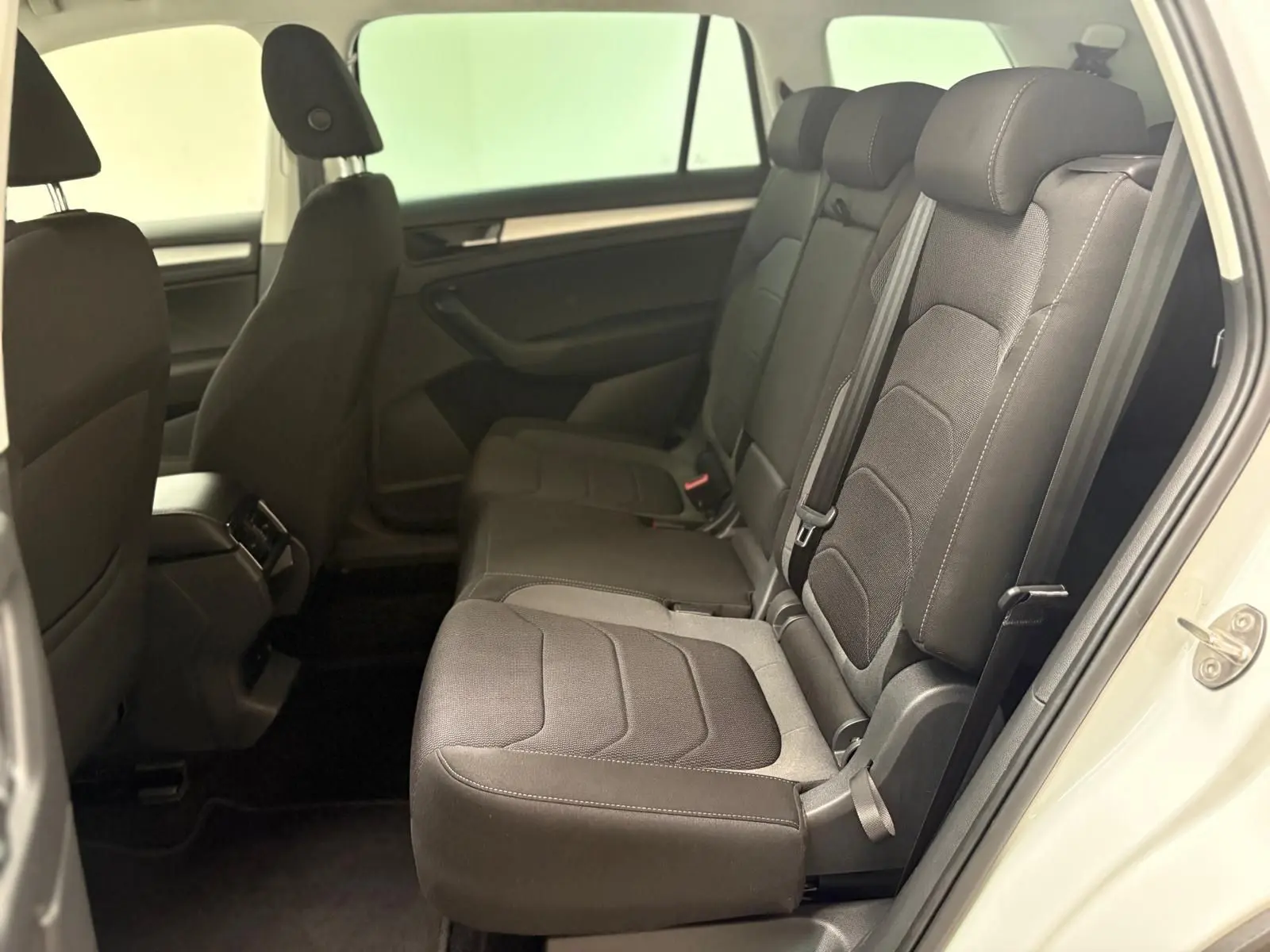 Vue intérieure côté droit sur la banquette arrière noire du Skoda Kodiaq blanc lune, montrant les sièges et ceintures.