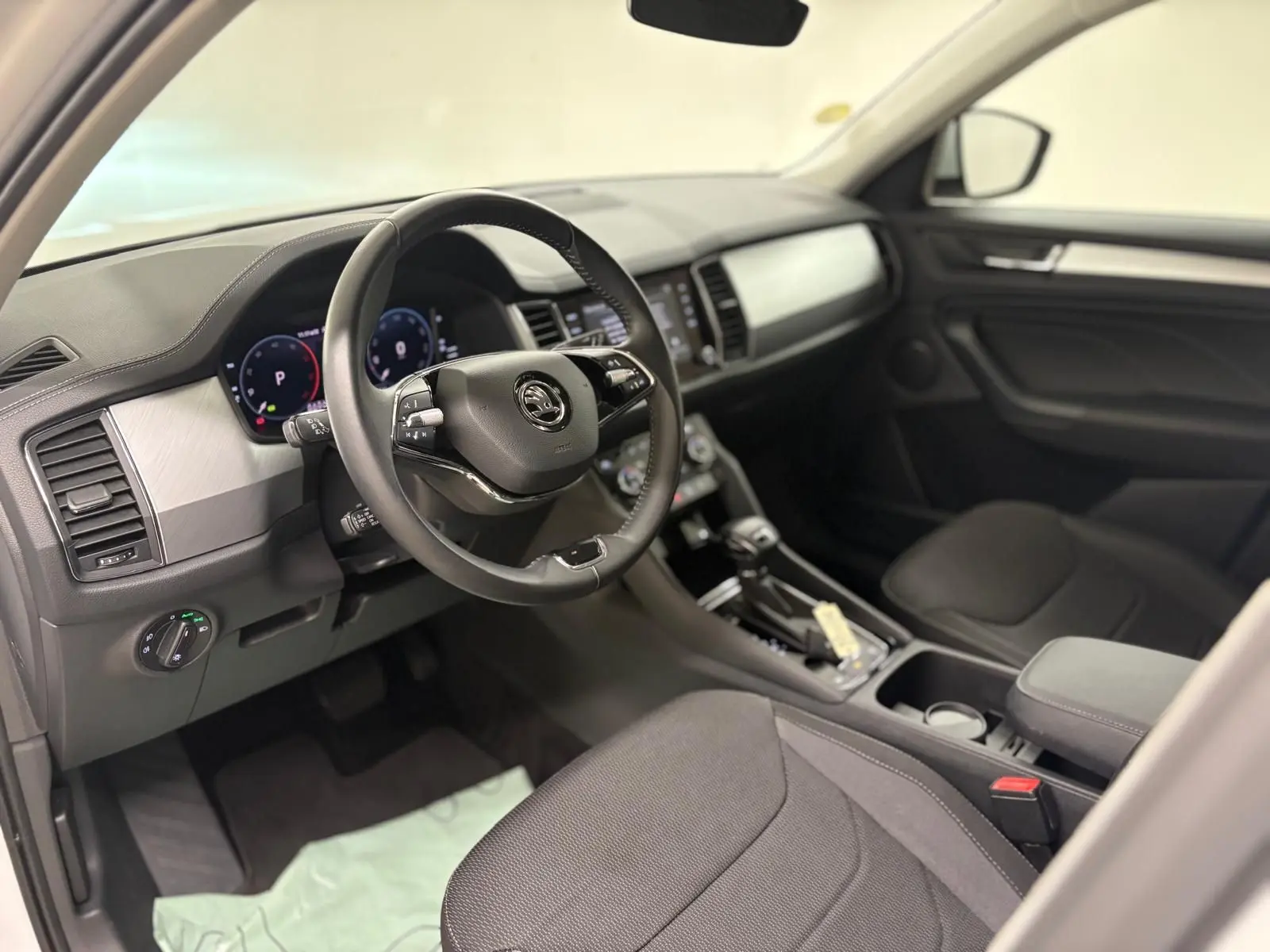 Intérieur avant droit du Skoda Kodiaq blanc lune 2022, avec tableau de bord moderne et volant multifonction noir.