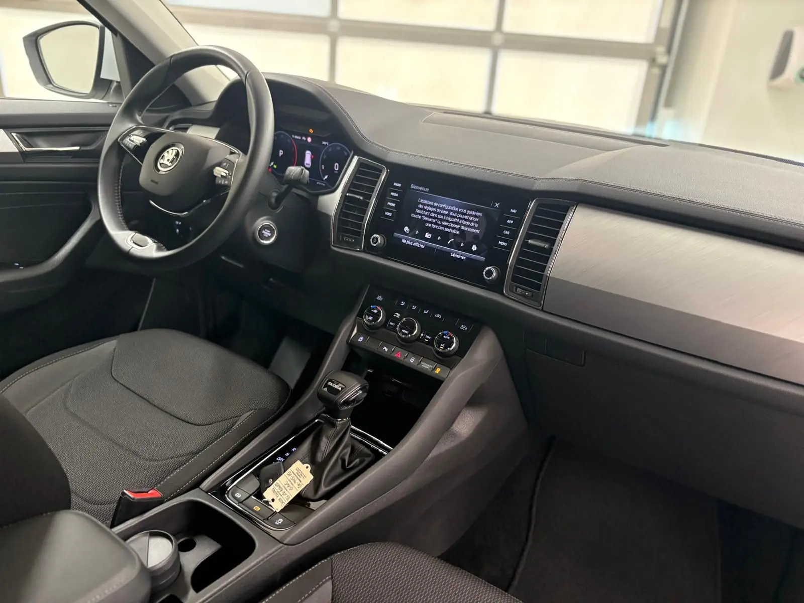 Intérieur avant du Skoda Kodiaq blanc lune 2022, tableau de bord moderne avec écran tactile et volant multifonction noir.