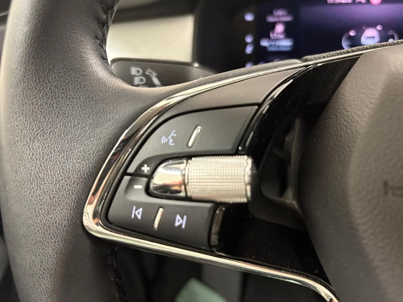 Gros plan sur les commandes du volant du Skoda Kodiaq 2022, mettant en valeur la molette métallique et les boutons rétroéclairés.