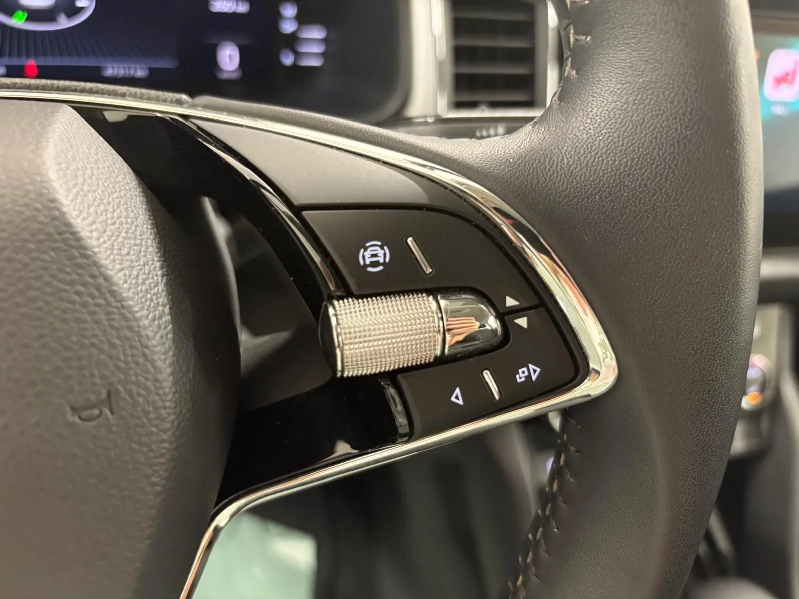 Gros plan sur les commandes du volant du Skoda Kodiaq blanc Lune, soulignant le bouton de régulateur de vitesse.