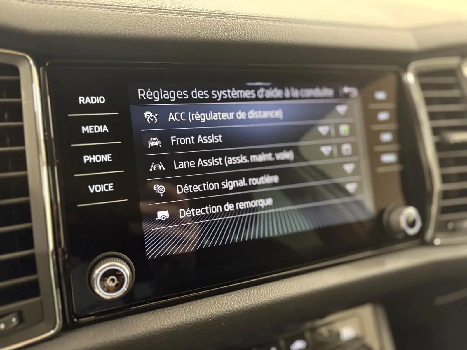 Écran tactile central du Skoda Kodiaq blanc Lune 2022 affichant les réglages d'aide à la conduite.