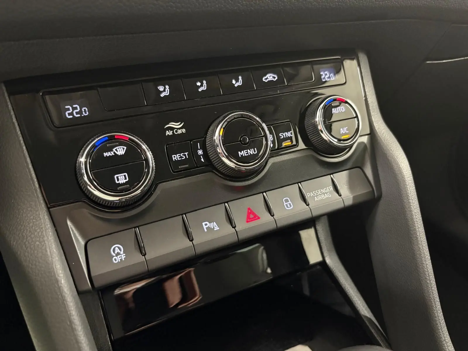 Gros plan sur la console centrale du Skoda Kodiaq blanc lune, montrant les commandes de climatisation et les boutons fonctionnels.