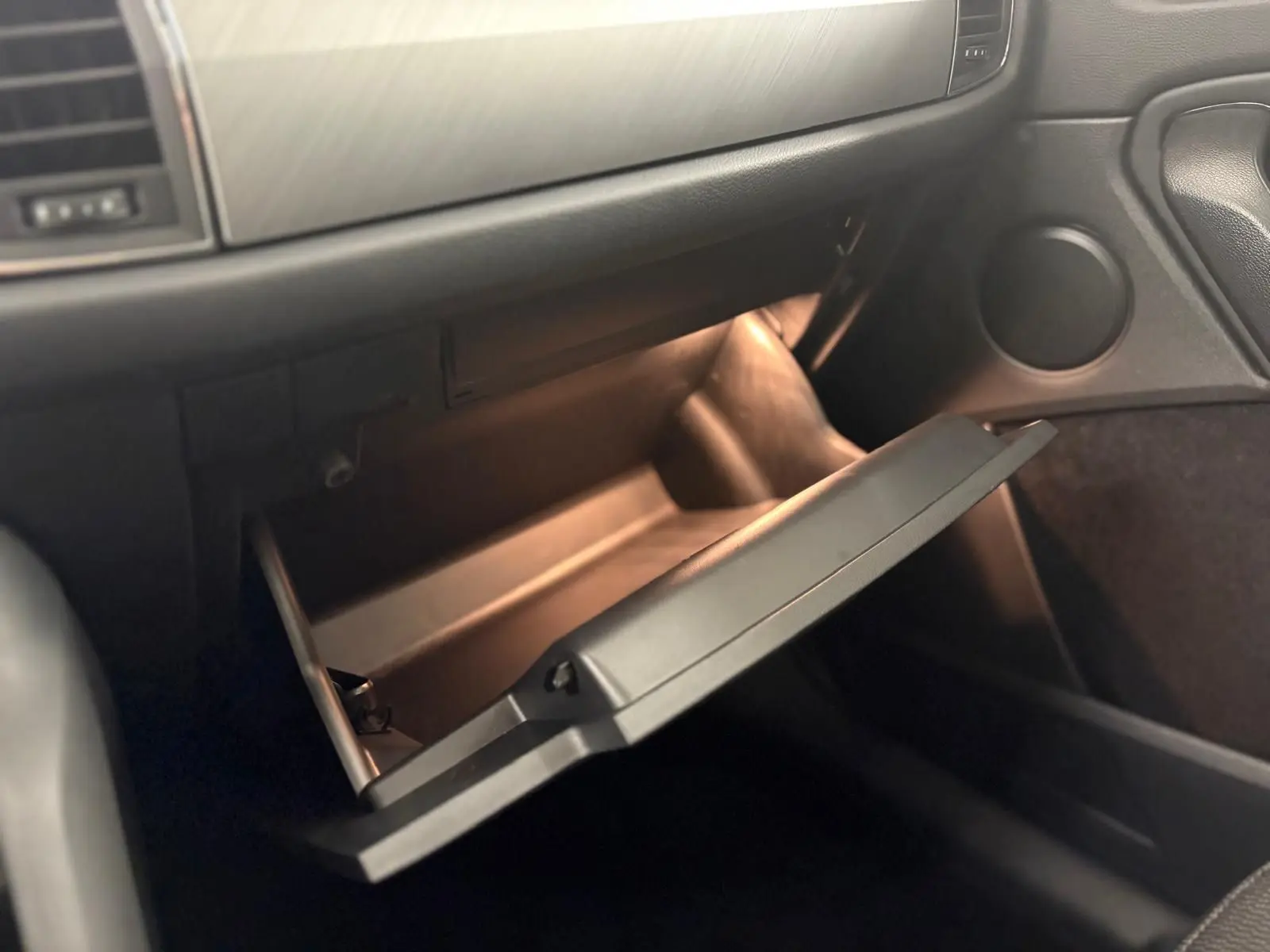 Intérieur du SKODA KODIAQ 2022 vue côté passager sur la boîte à gants ouverte avec éclairage intérieur doux.