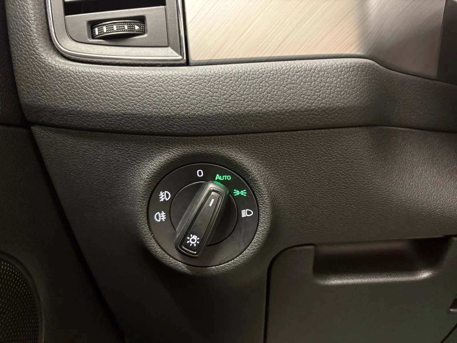 Gros plan sur le bouton de commande des phares dans l'habitacle noir du Skoda Kodiaq blanc Lune 2022.
