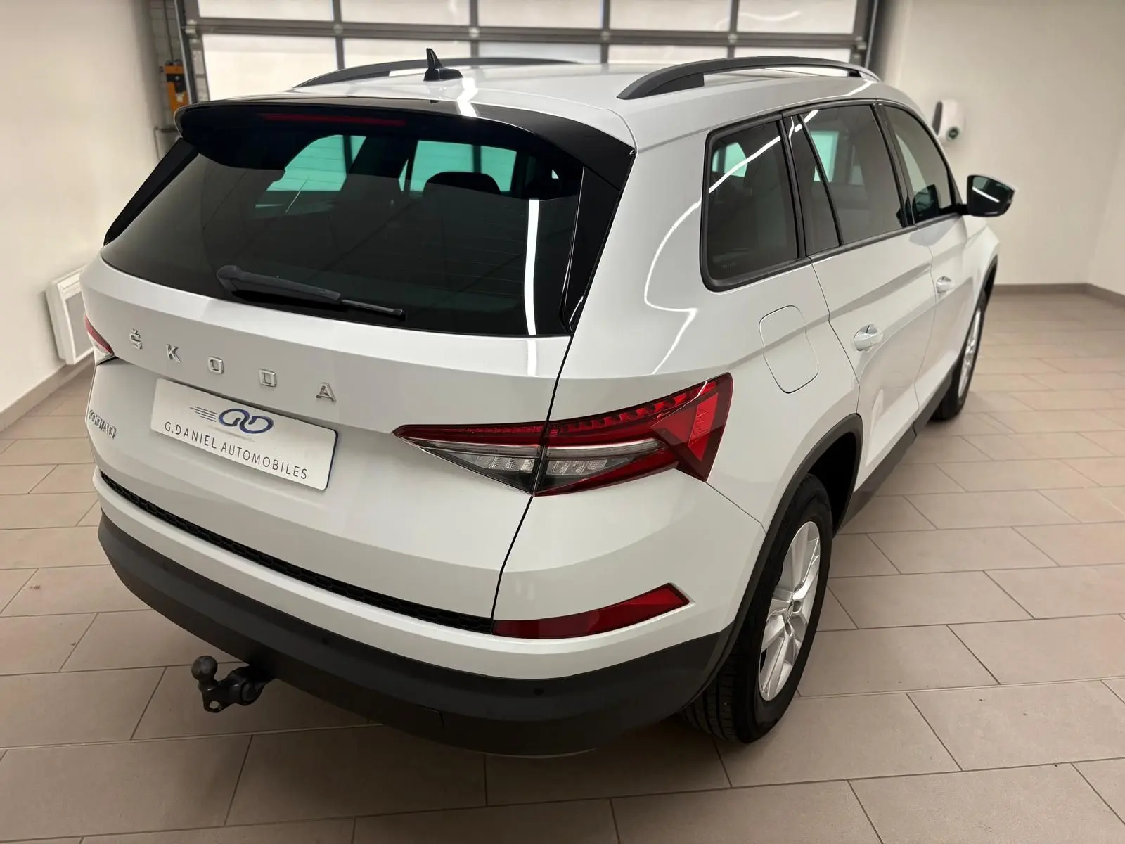 Vue 3/4 arrière droite du Skoda Kodiaq blanc lune 2022 avec crochet d'attelage escamotable et vitres teintées.