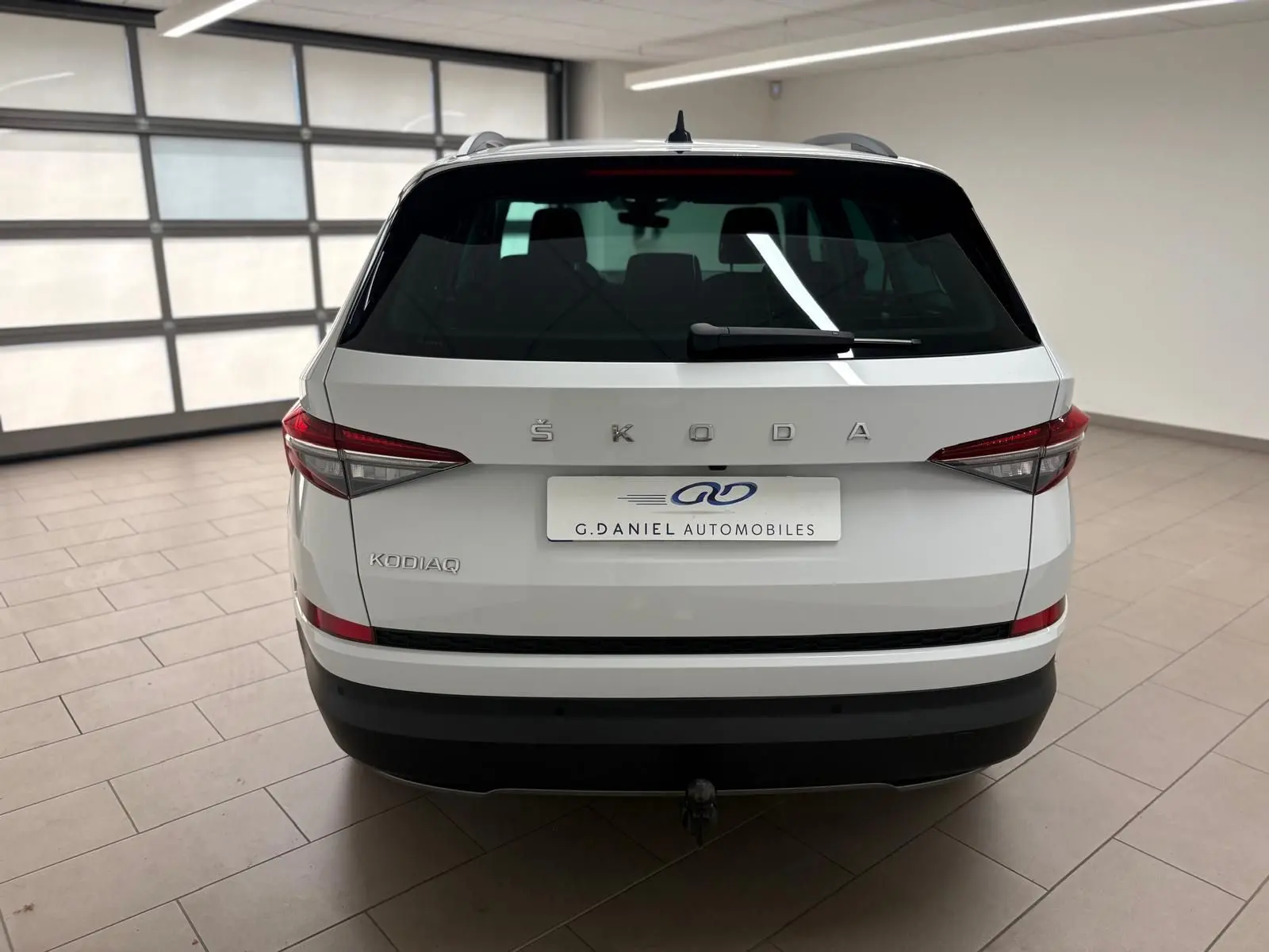 Vue arrière d'un Skoda Kodiaq blanc lune 2022 avec attelage escamotable et feux arrière LED dans un garage.