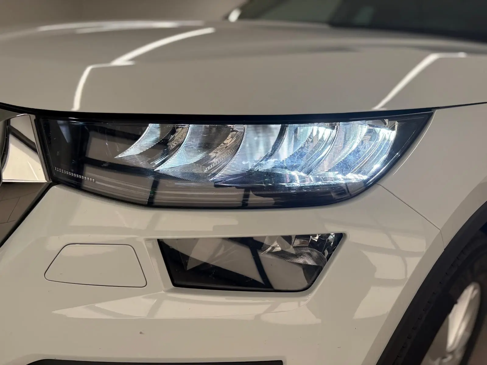 Gros plan sur le phare avant droit du Skoda Kodiaq blanc lune 2022, mettant en valeur son design moderne et lumineux.