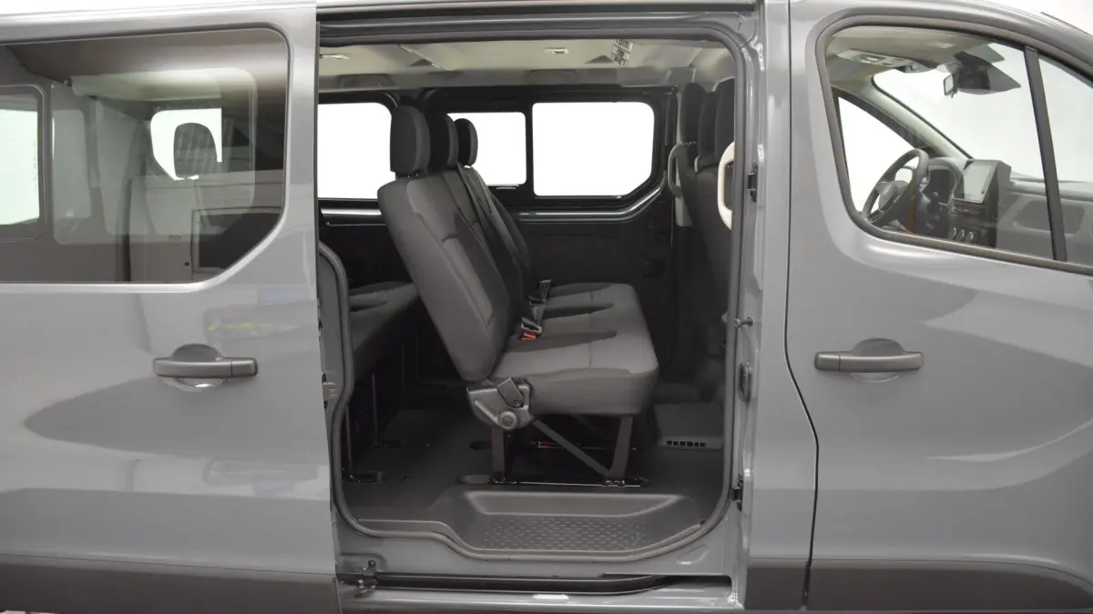 Vue latérale gauche du Renault Trafic Fourgon gris clair 2025, portes ouvertes montrant la banquette 3 places rabattable de la 3ème rangée.