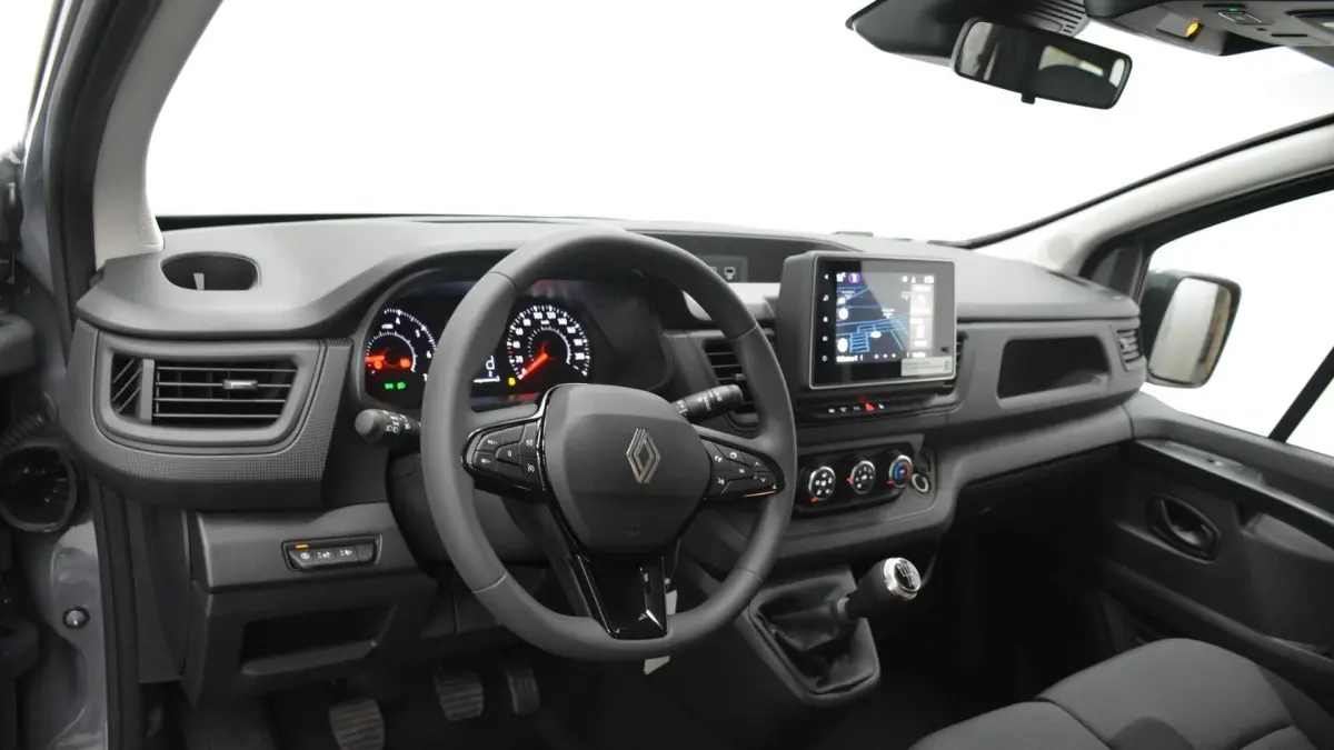 Vue intérieure avant du Renault Trafic Fourgon gris clair 2025, avec tableau de bord central tactile et volant multifonctions.