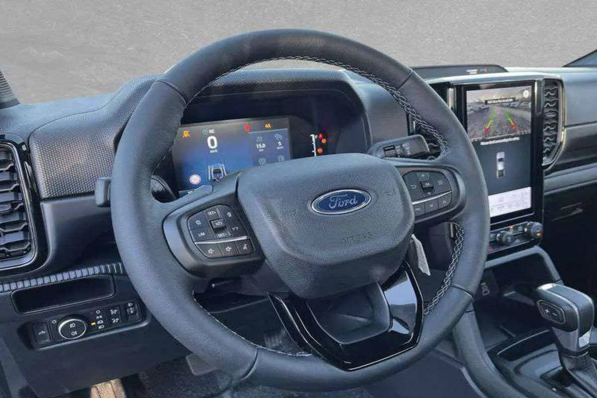 Vue intérieure centrée sur le volant cuir multifonctions du Ford Ranger 2025 avec écran tactile et tableau de bord numérique.