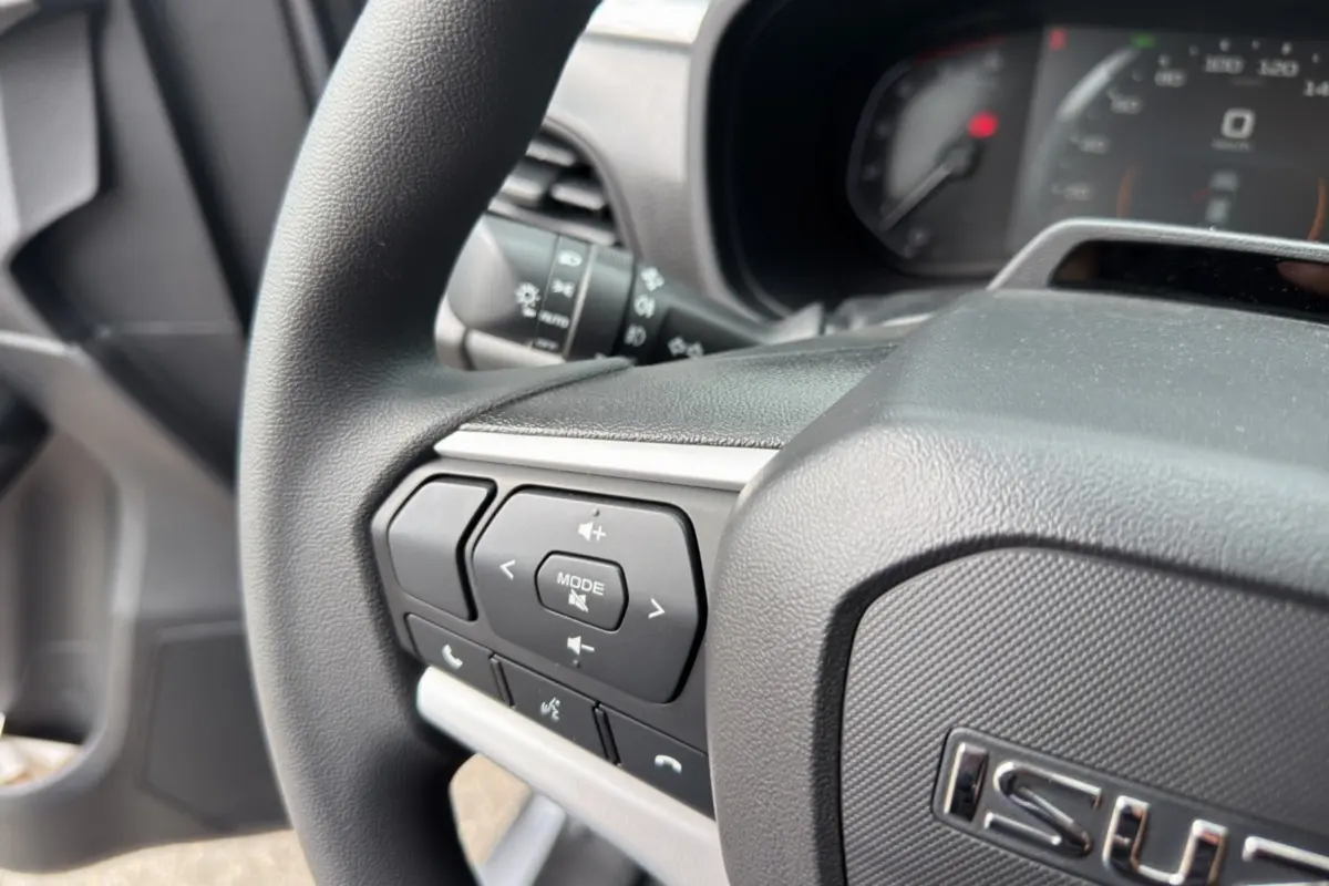 Gros plan sur le volant multifonctions côté gauche de l'Isuzu D-MAX 2026, avec commandes audio et téléphone.