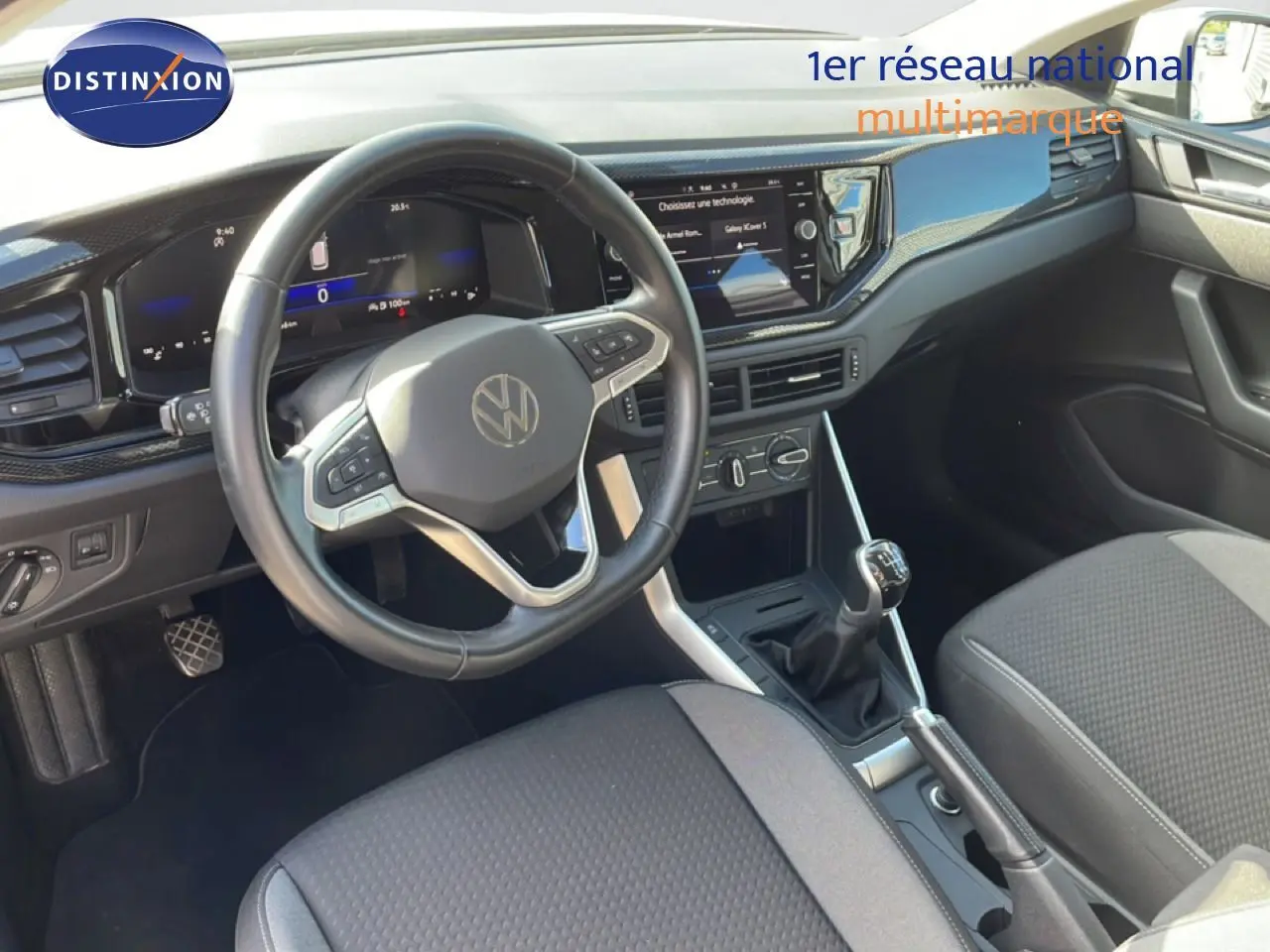 Vue intérieure côté conducteur du Volkswagen Taigo 2022, tableau de bord noir avec volant cuir et boîte manuelle visible.