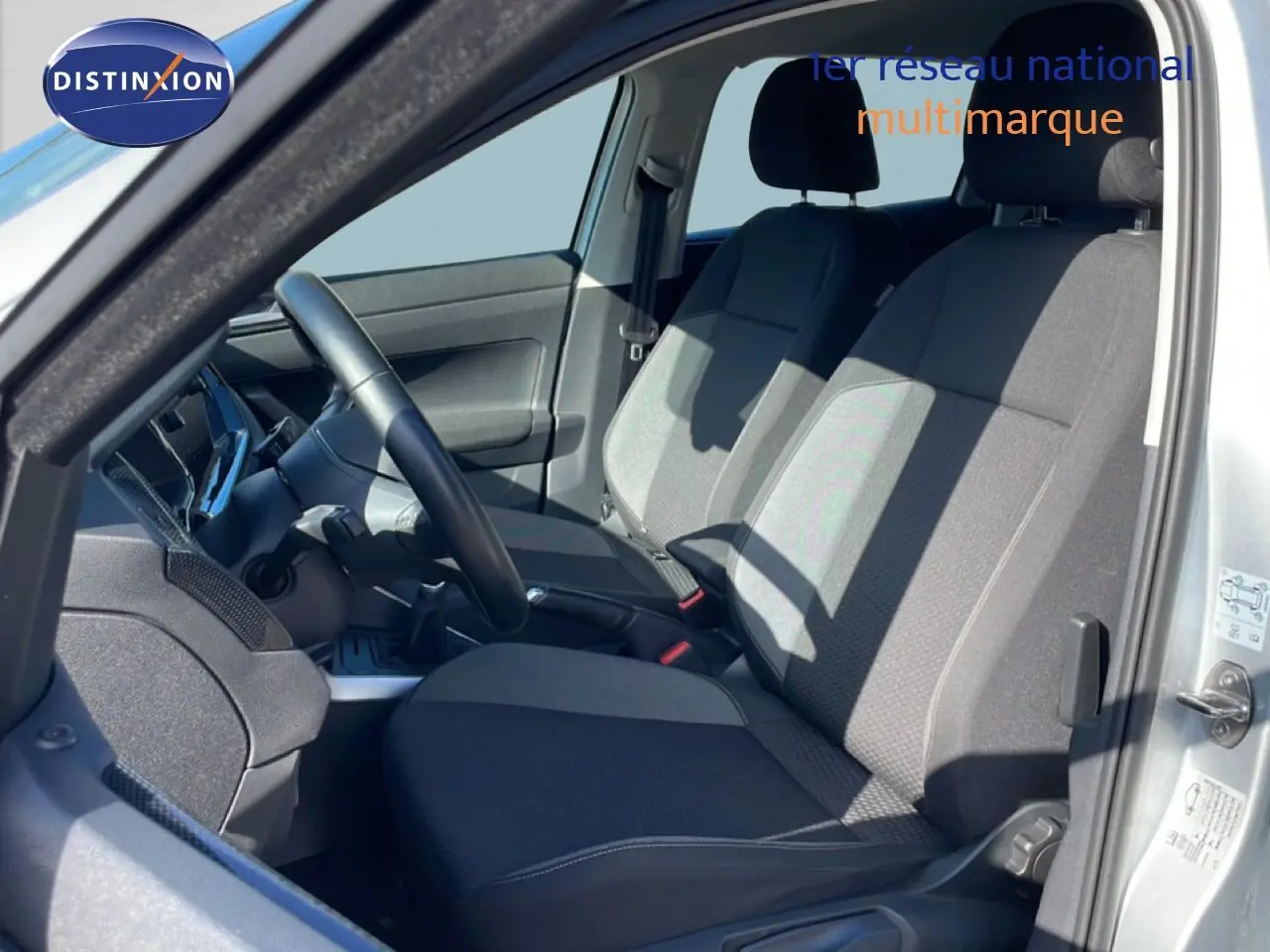 Vue intérieure côté gauche du Volkswagen Taigo 2022 argent, montrant les sièges avant en tissu gris et le volant cuir.
