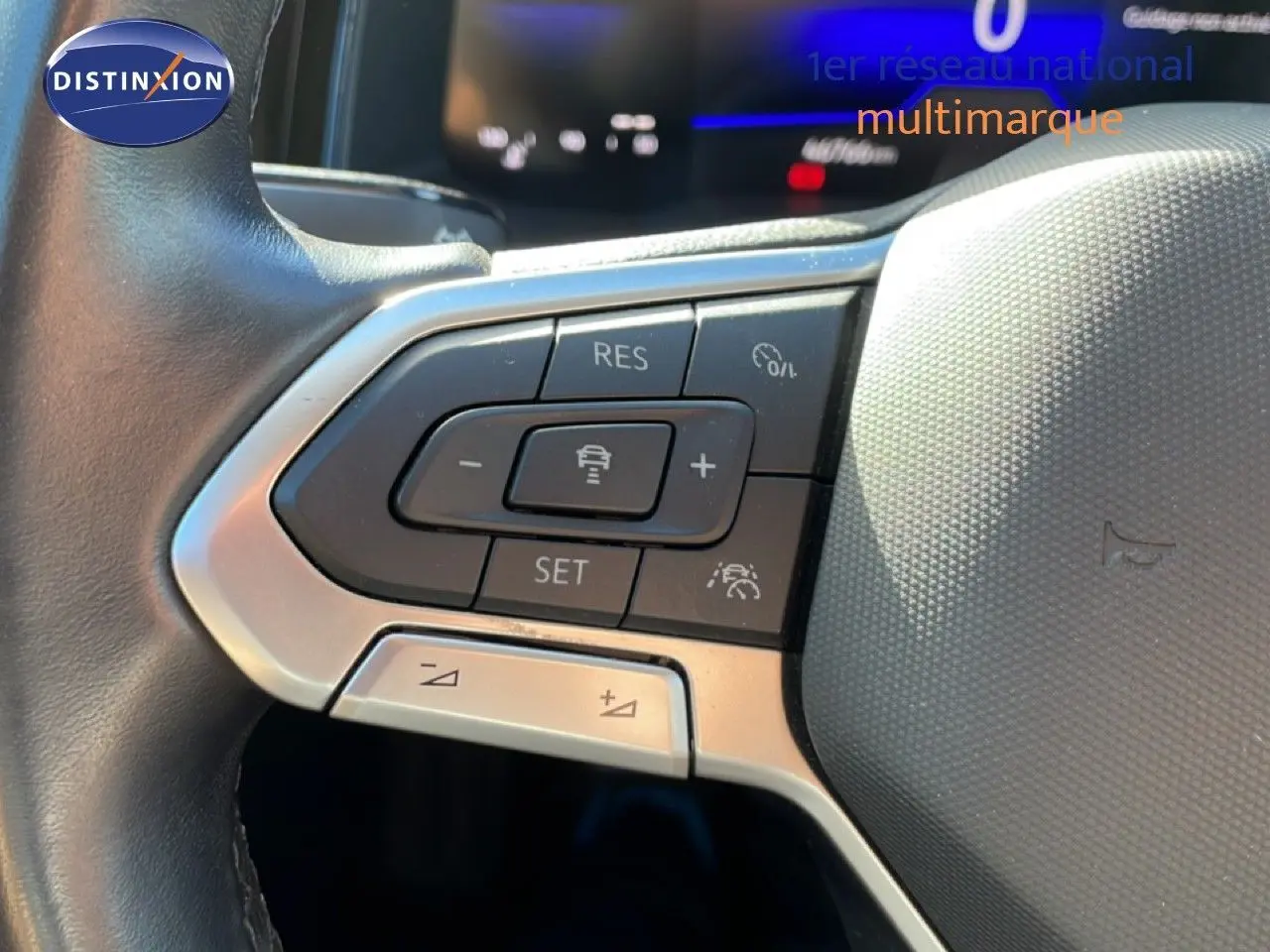 Gros plan sur les commandes au volant côté gauche du Volkswagen Taigo 2022 en reflet d'argent métal, avec boutons de régulateur de vitesse.