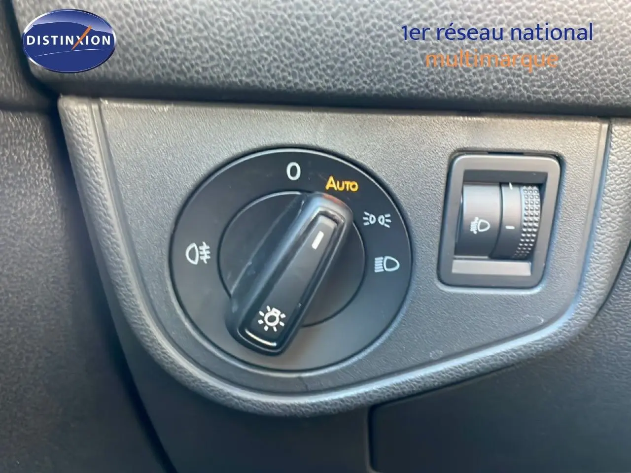 Gros plan sur le bouton de commande des phares avec réglage automatique dans l'habitacle noir d'un Volkswagen Taigo.