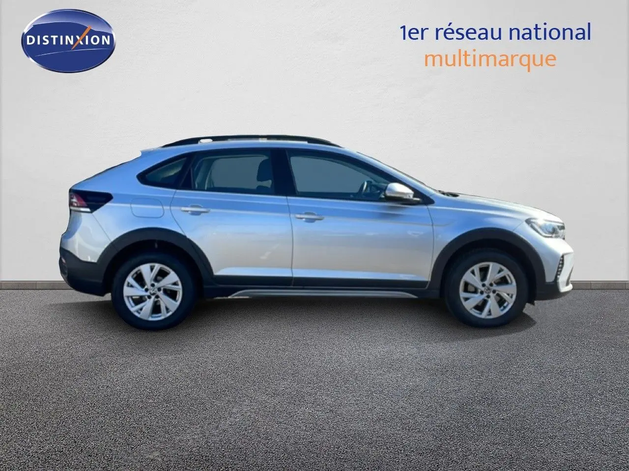 Vue de profil côté gauche d'un Volkswagen Taigo 2022 couleur reflet d'argent métal avec jantes alliage et barres de toit.