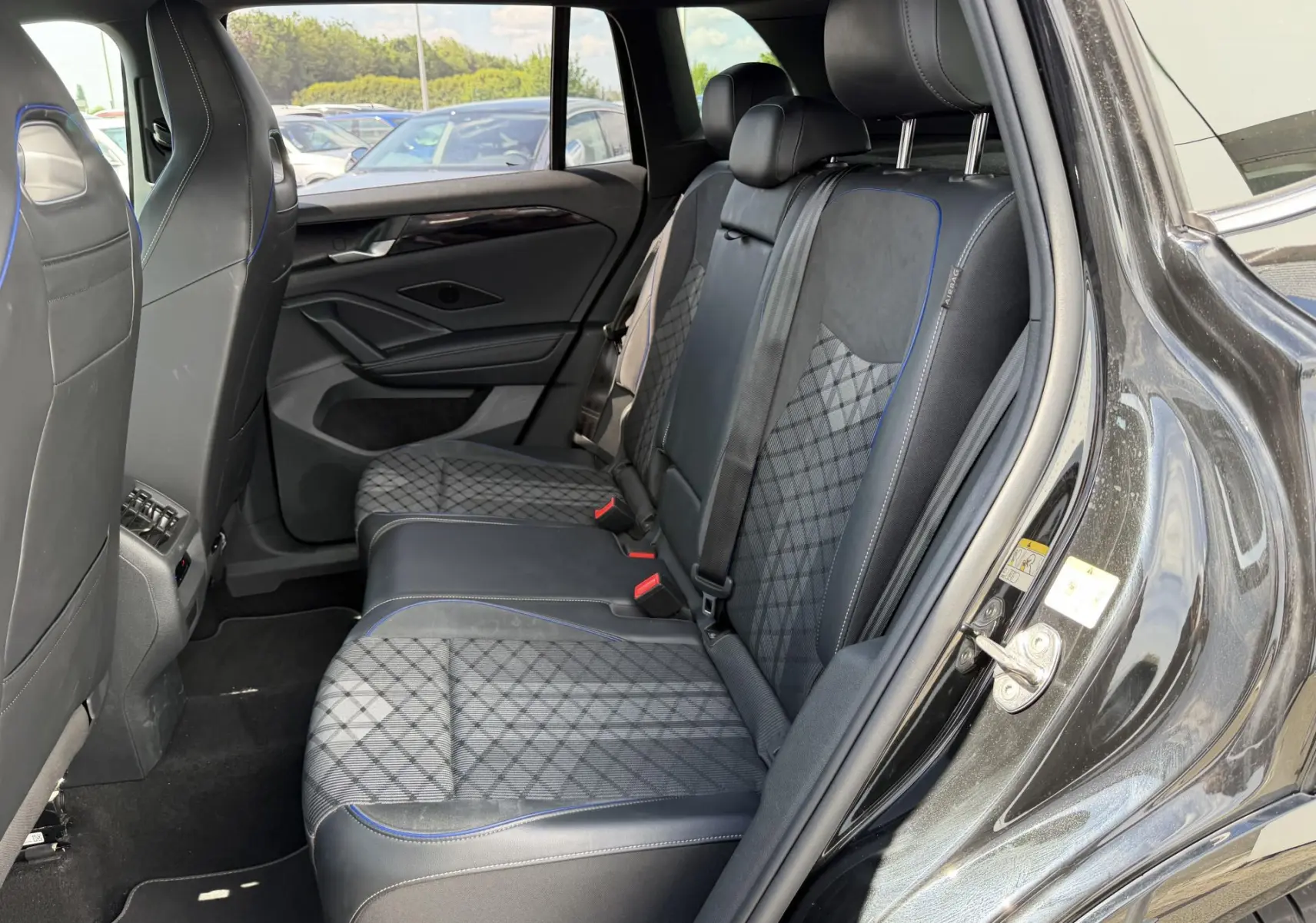 Vue intérieure côté droit des sièges arrière en tissu et cuir noir avec surpiqûres bleues du Volkswagen Tiguan 2025 noir.