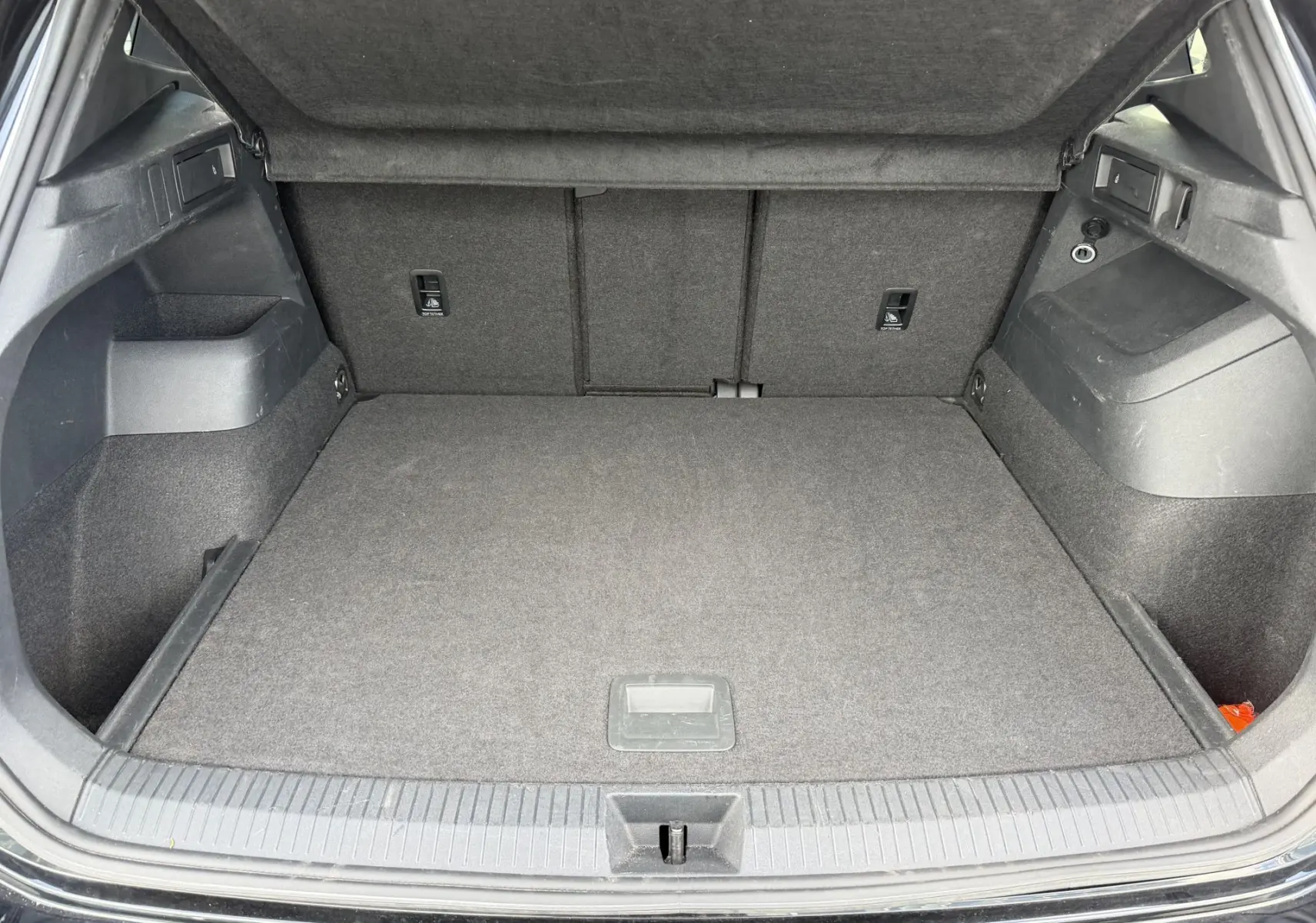 Coffre ouvert vu de l'arrière d'un Volkswagen Tiguan noir, espace de chargement propre et bien agencé.