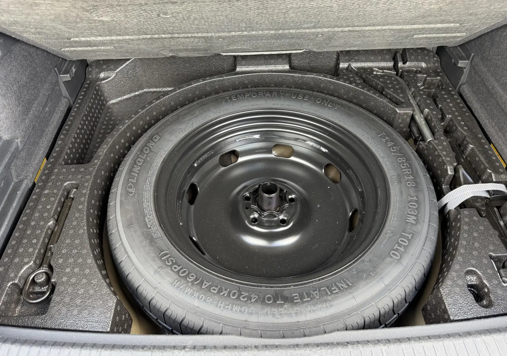 Vue rapprochée de la roue de secours compacte noire dans le coffre du Volkswagen Tiguan 2025.