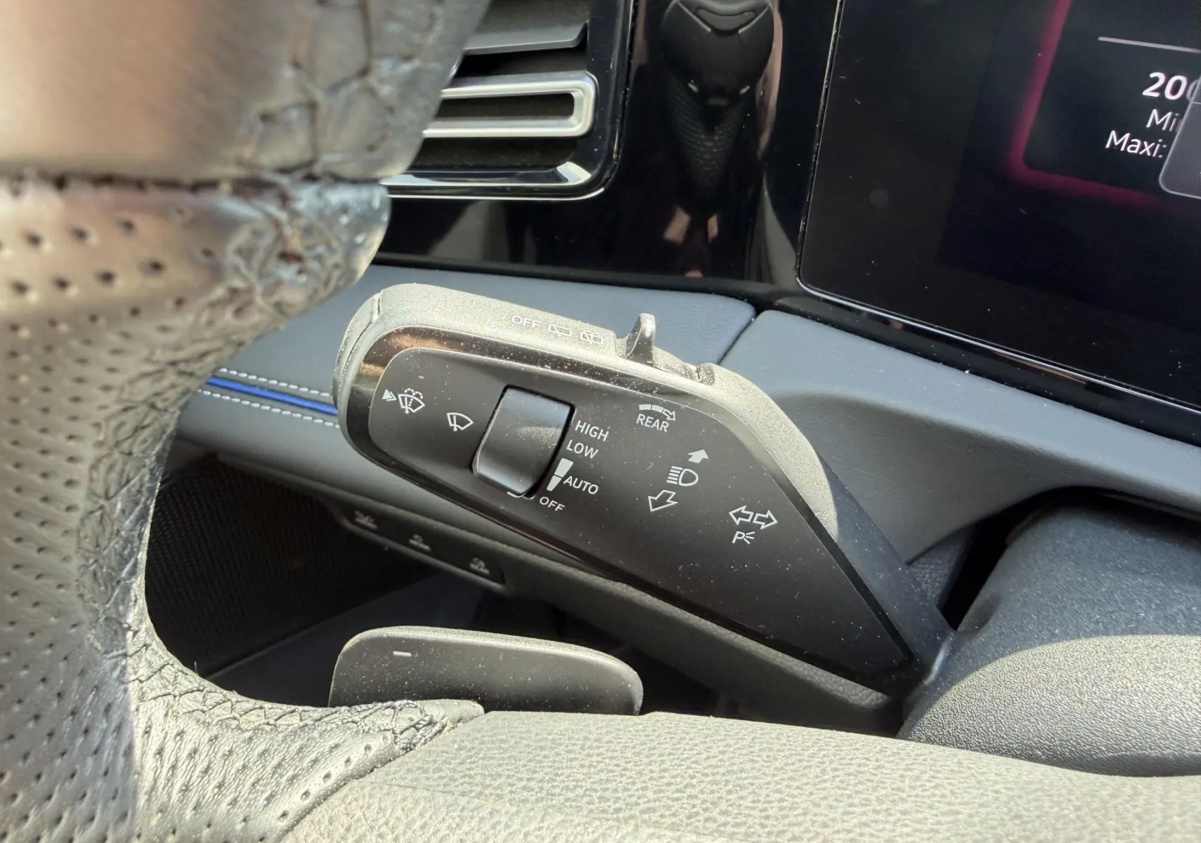 Gros plan sur la commande de l’essuie-glace côté gauche du volant cuir perforé dans l’habitacle noir du Volkswagen Tiguan 2025.