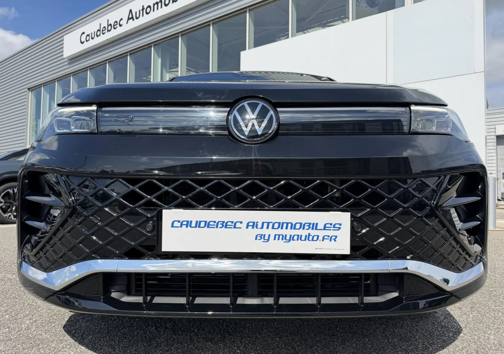 Vue frontale rapprochée du Volkswagen Tiguan noir avec calandre en losanges et logo VW lumineux au centre.