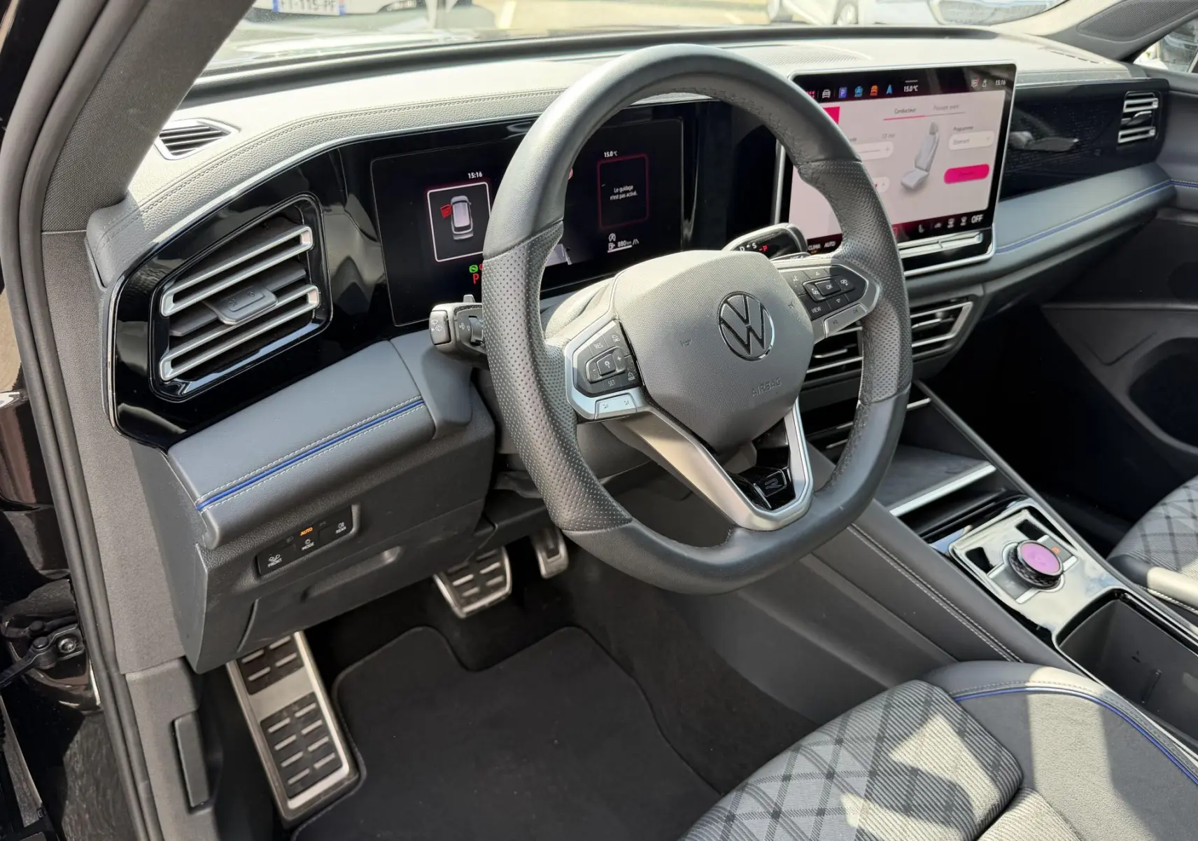 Vue intérieure côté conducteur du Volkswagen Tiguan 2025 noir, volant cuir multifonction et écran digital tactile.