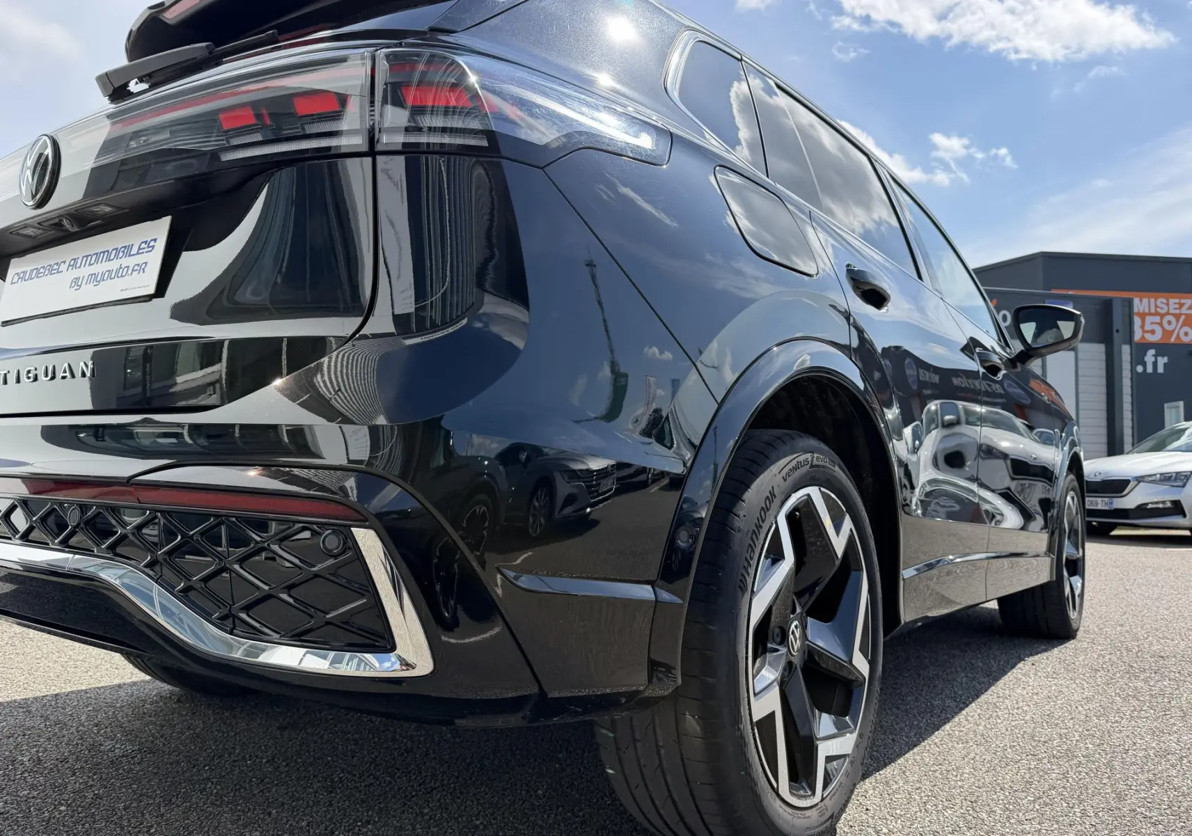Vue 3/4 arrière droite du Volkswagen Tiguan noir 2025 avec jantes alliage 19 pouces et feux arrière LED 3D visibles.