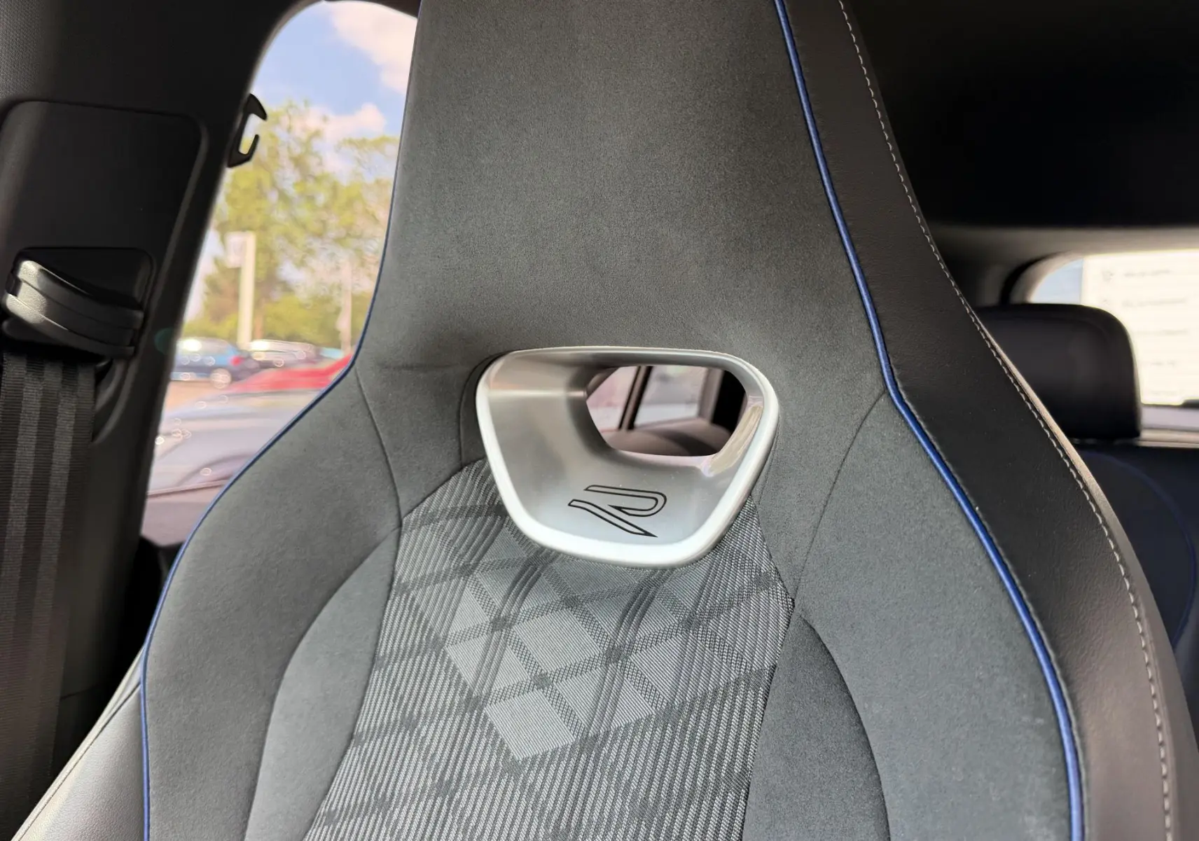 Gros plan sur le siège avant sport gris avec surpiqûres bleues et logo R du Volkswagen Tiguan 2025.