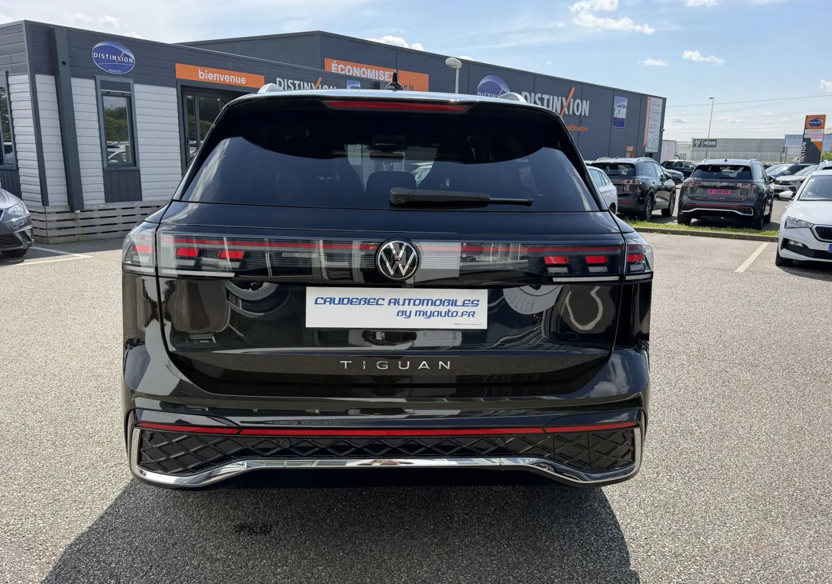 Vue arrière d'un Volkswagen Tiguan noir 2025 avec feux arrière LED 3D et logo VW centré sur un parking extérieur.