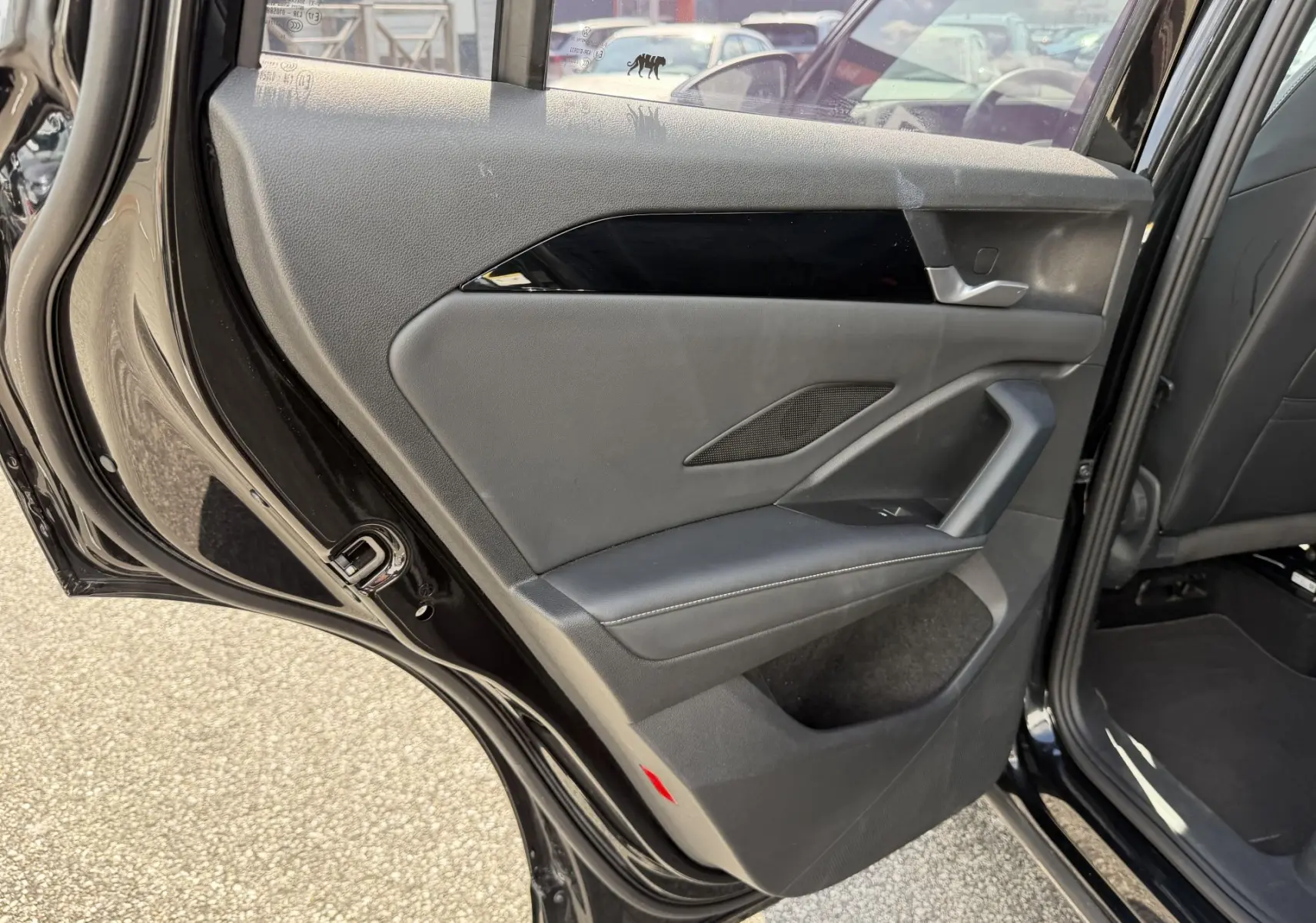 Vue intérieure de la porte arrière droite noire du Volkswagen Tiguan 2025, avec garniture grise et insert noir brillant.
