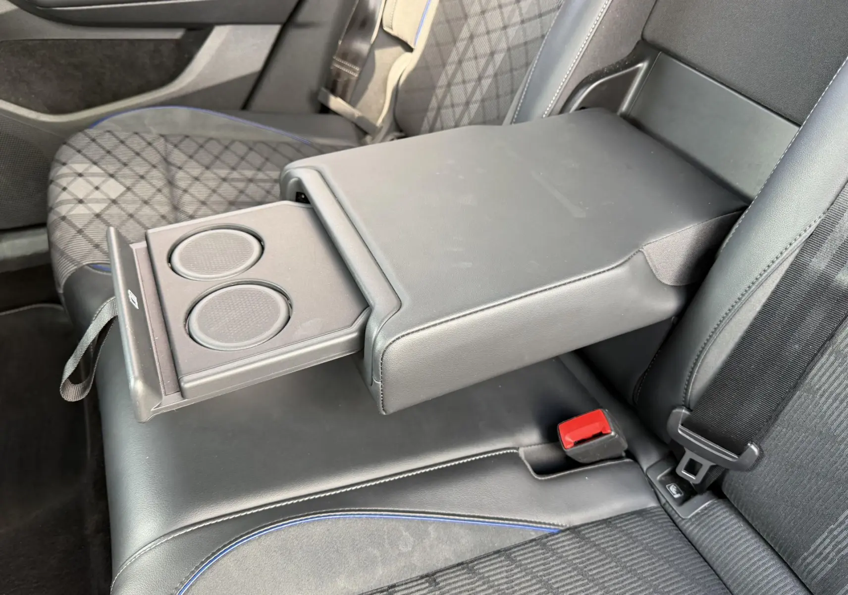 Vue rapprochée de l'accoudoir central arrière noir avec porte-gobelets déployé sur les sièges arrière du Volkswagen Tiguan 2025.
