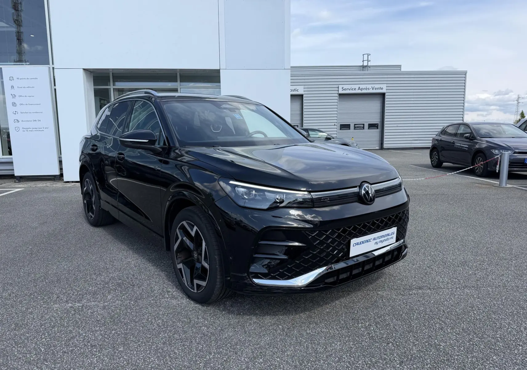 Volkswagen Tiguan noir en vue 3/4 avant gauche avec jantes alliage noir et calandre R-Line visible.