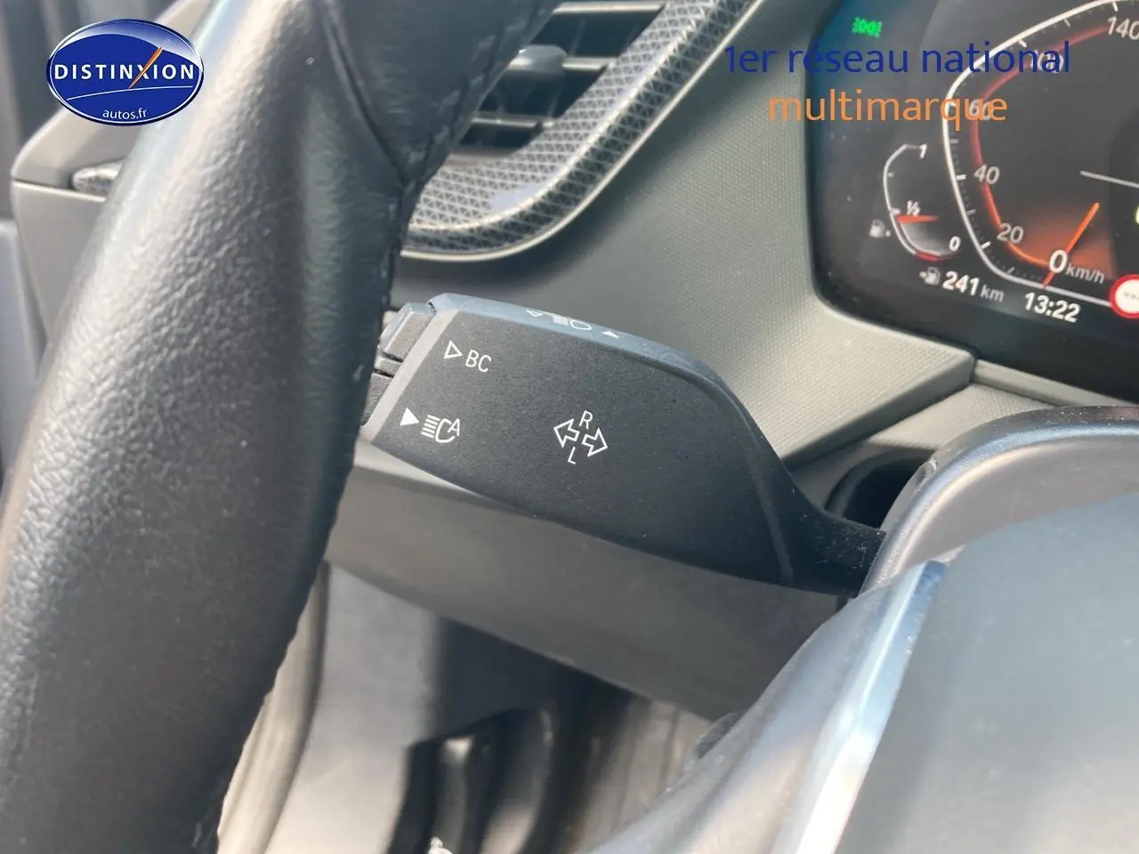 Gros plan sur la manette de clignotant à gauche du volant d'une BMW Série 1 gris foncé, tableau de bord en arrière-plan.