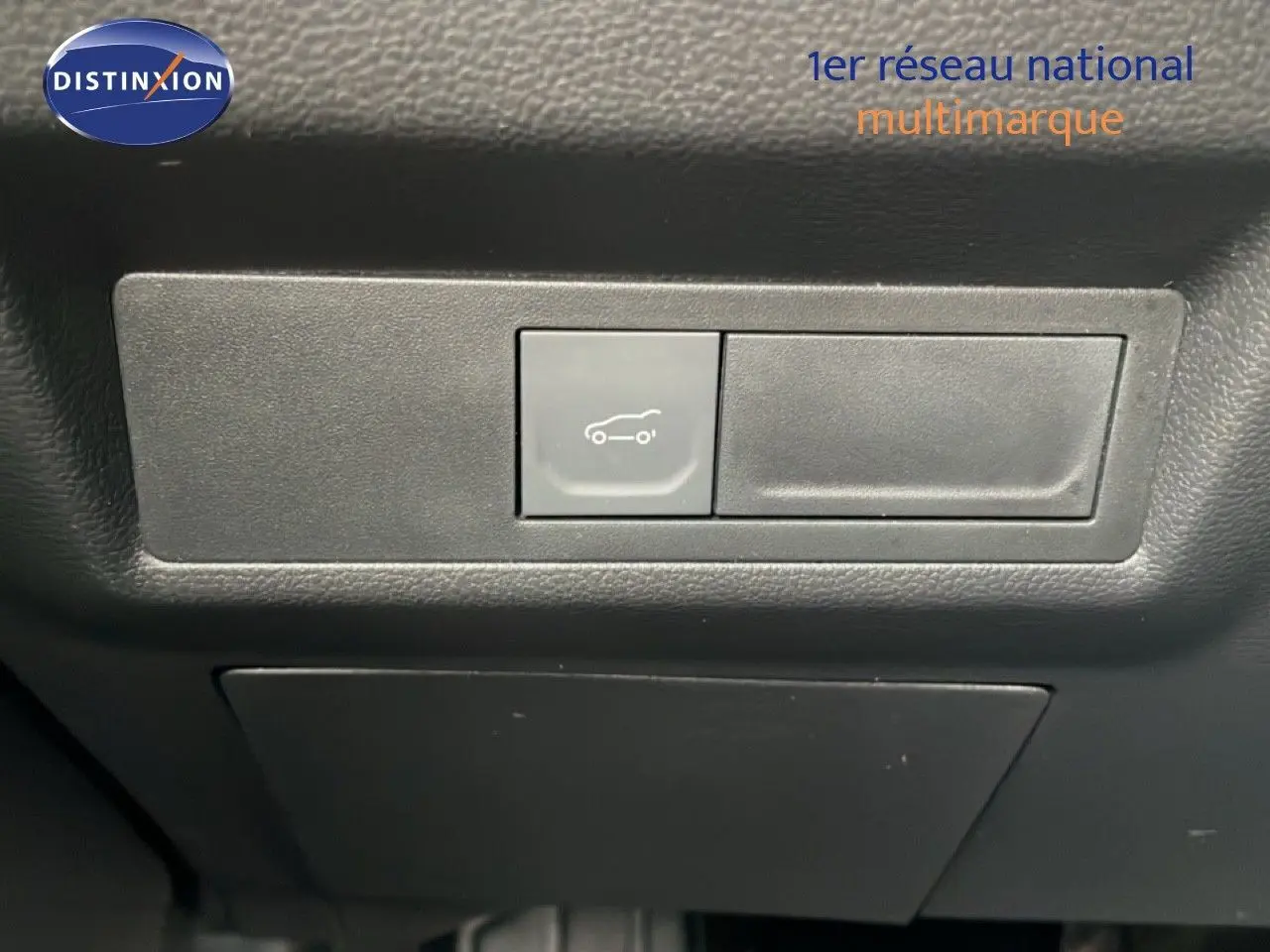 Gros plan sur le bouton d'ouverture du coffre dans l'habitacle noir du Renault Symbioz E-Tech Full Hybrid 2025.