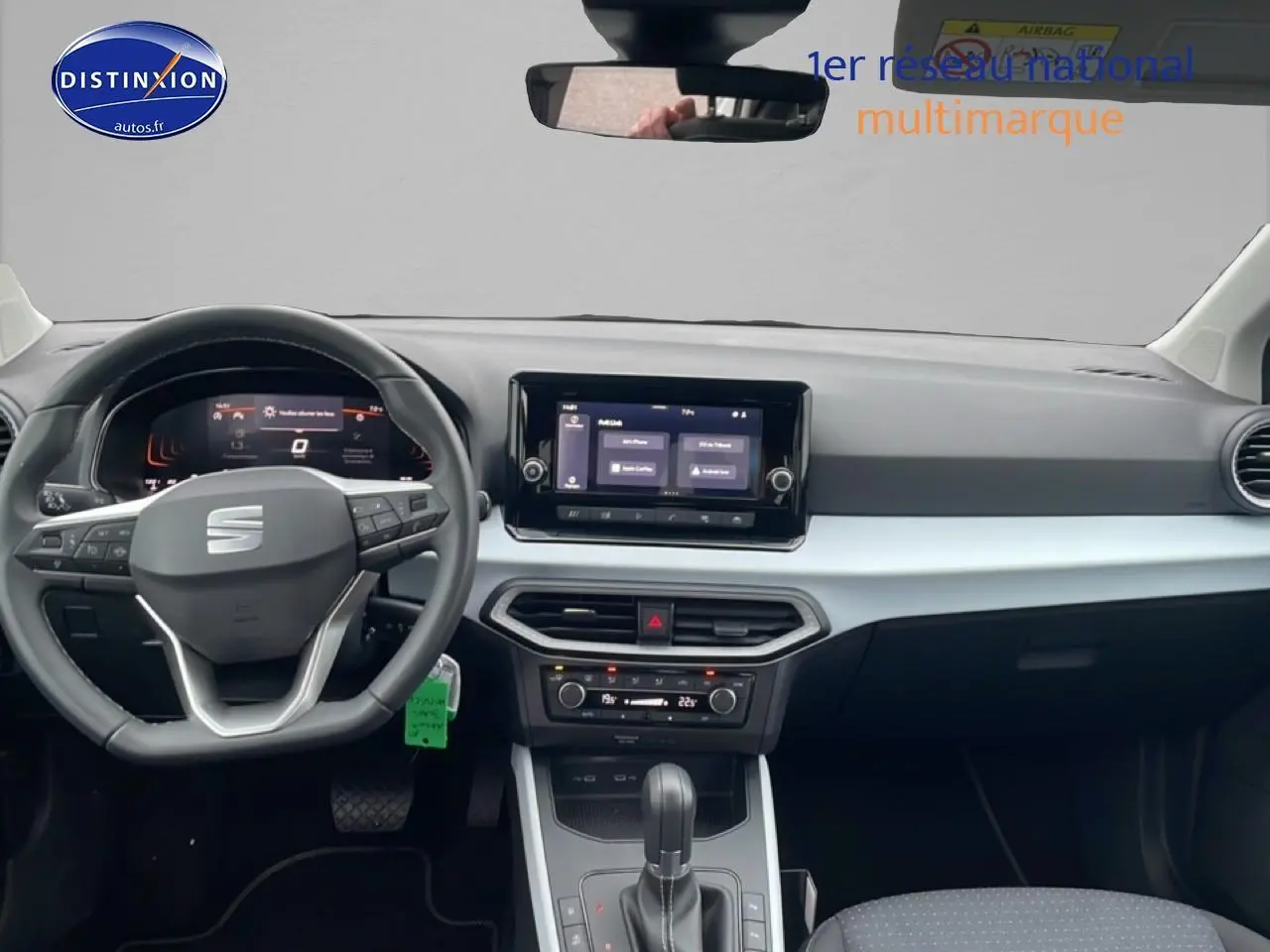 Vue intérieure frontale du tableau de bord et volant cuir noir du SEAT Arona blanc Nevada 2025 avec écran tactile central.